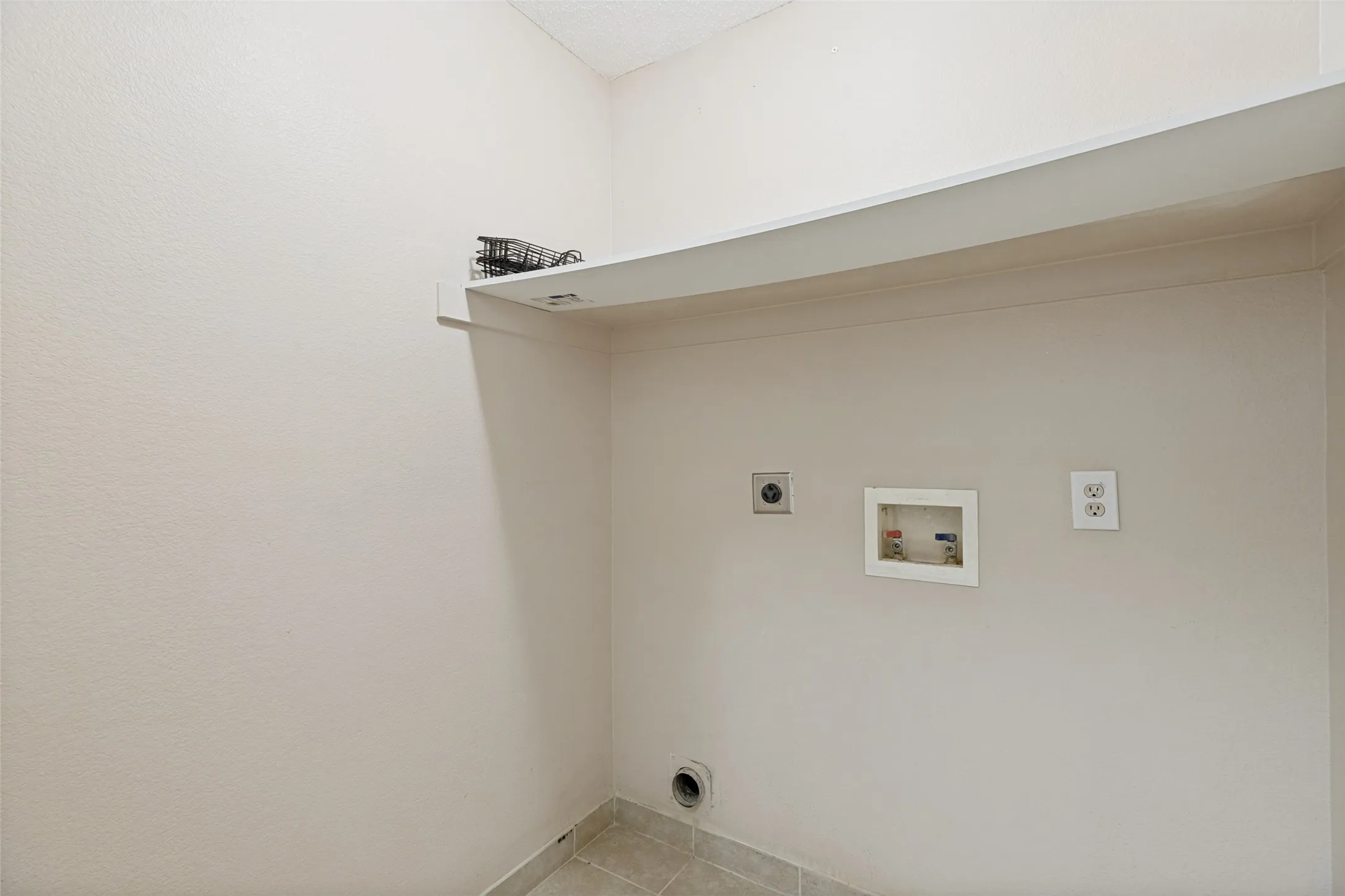 Laundry area with tile flooring and a built-in wall shelf