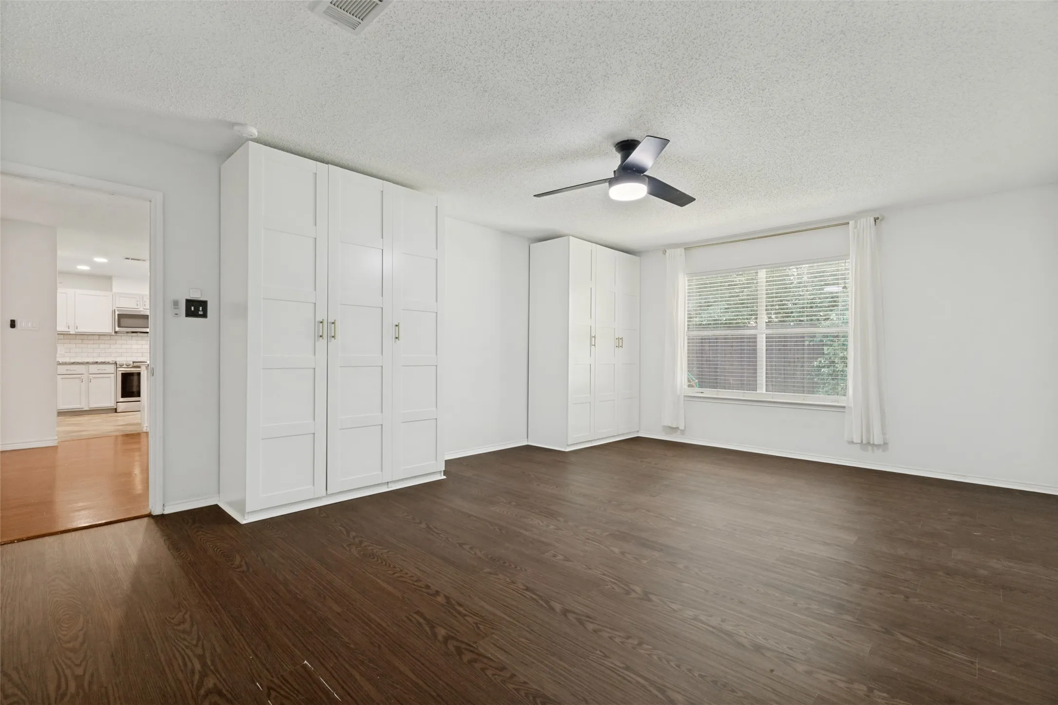 Dark wood-finish flooring with white walls and built-in white cabinetry
