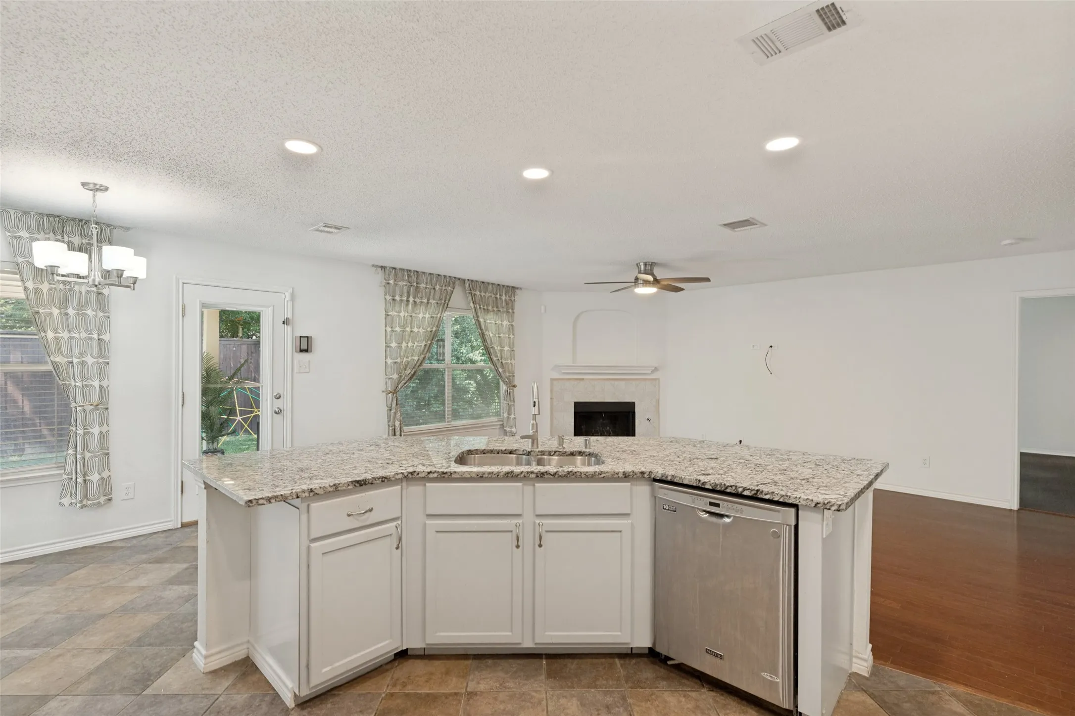 Kitchen island with granite countertops, stainless steel sink, and integrated dishwasher