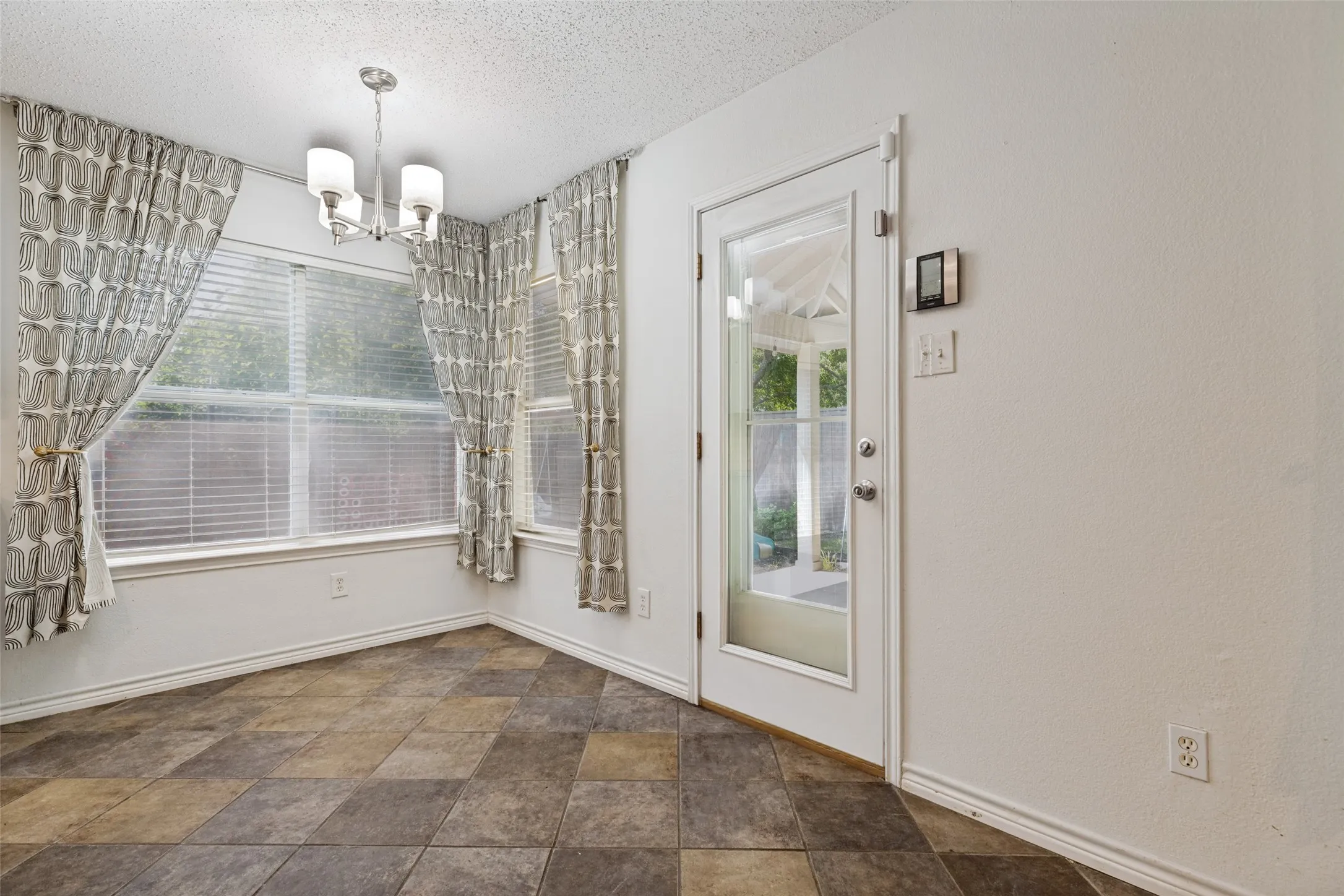 Recessed corner with multi-pane windows, a full-lite exterior door, and a modern chandelier