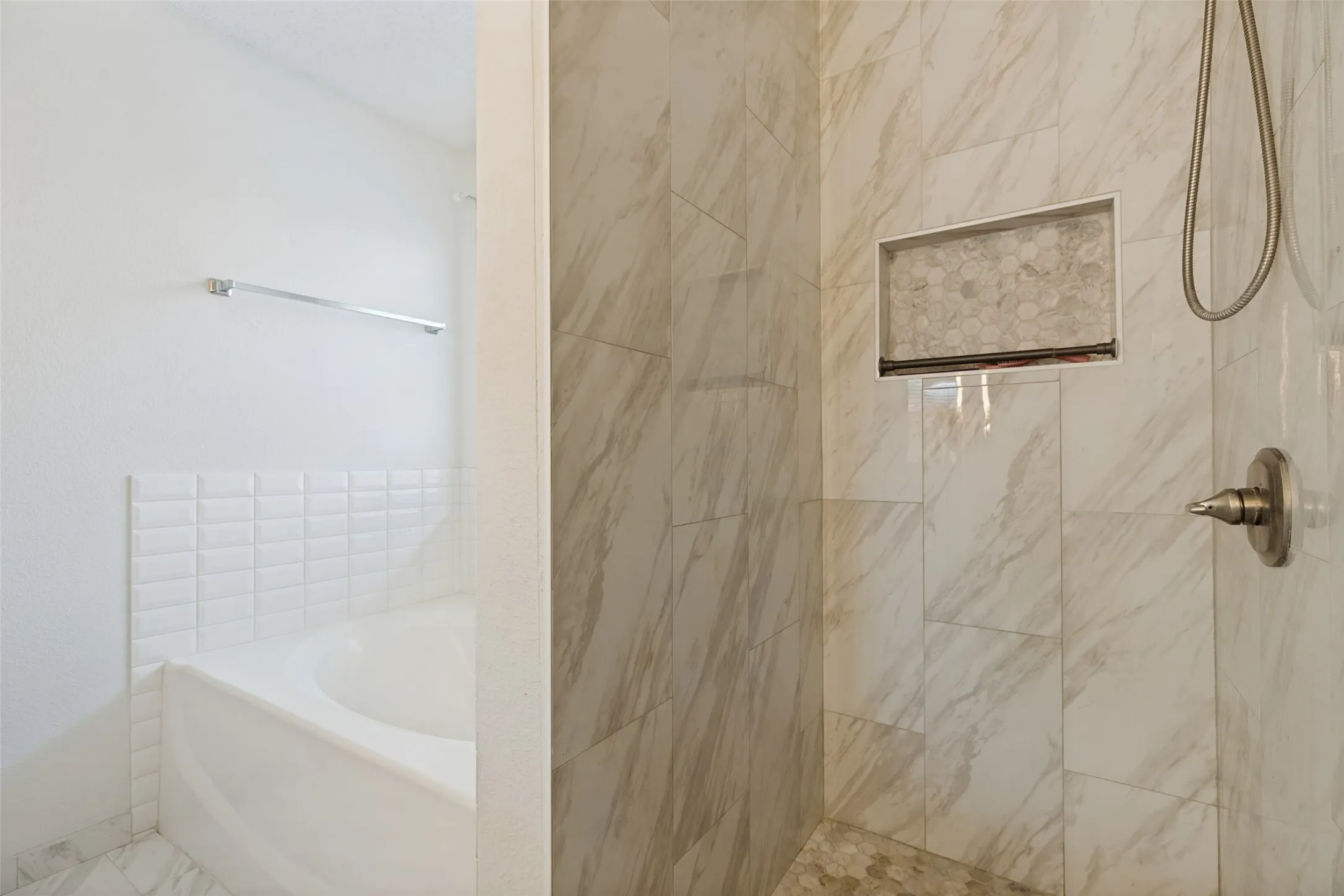 Shower with large format veined wall tile, built-in recessed shelf with mosaic tile, and brushed nickel fixtures