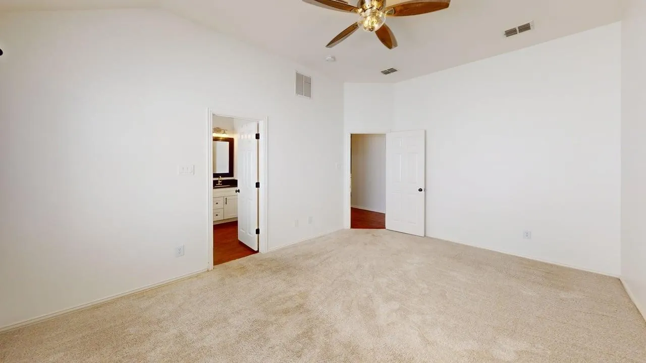 Carpeted room with vaulted ceilings and a ceiling fan