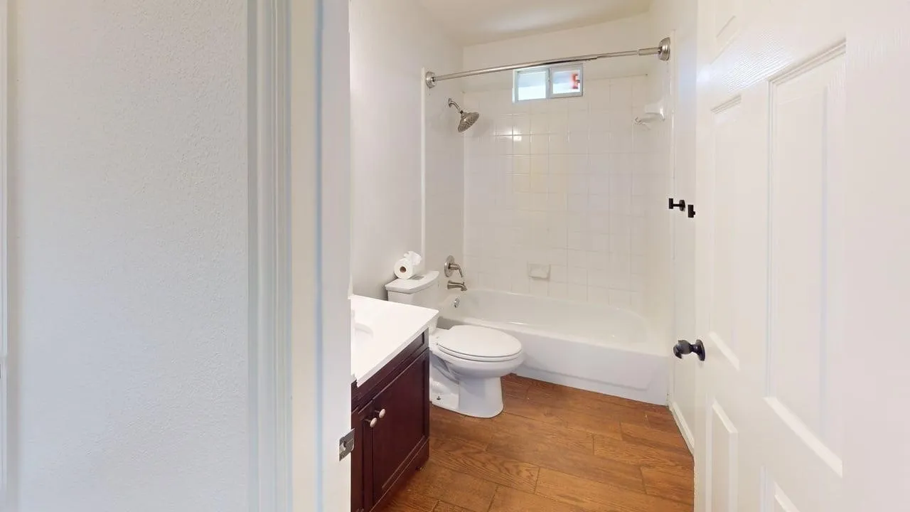 Spa-inspired bathroom featuring a wood-finish vanity with ample storage, ceramic countertop, and brushed nickel fixtures