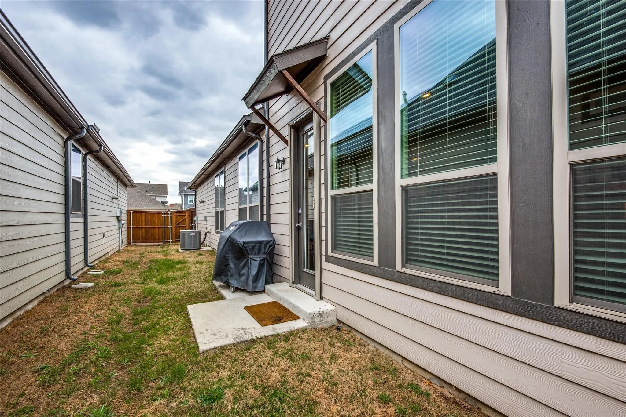 Spacious backyard retreat featuring a level lawn, modern composite patio area, and covered outdoor living space with large sliding glass doors
