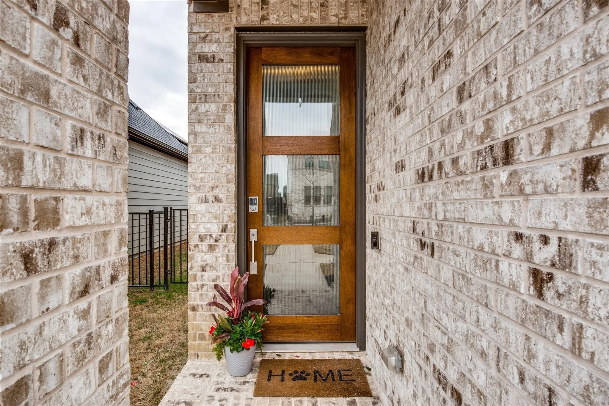Welcoming entry featuring a wood-frame glass door with multiple panes, flanked by substantial brick exterior walls in a neutral earth-tone finish