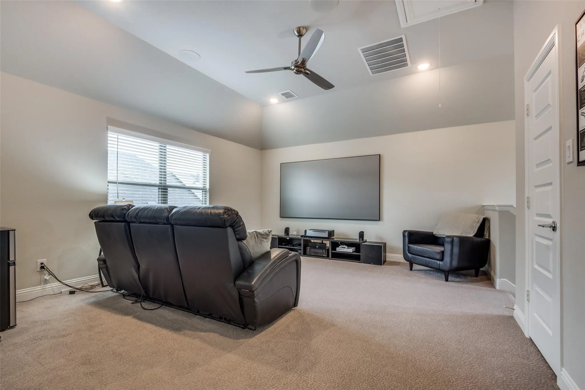 Spacious entertainment room featuring recessed lighting, a ceiling fan, a large screen, and neutral-toned carpeting
