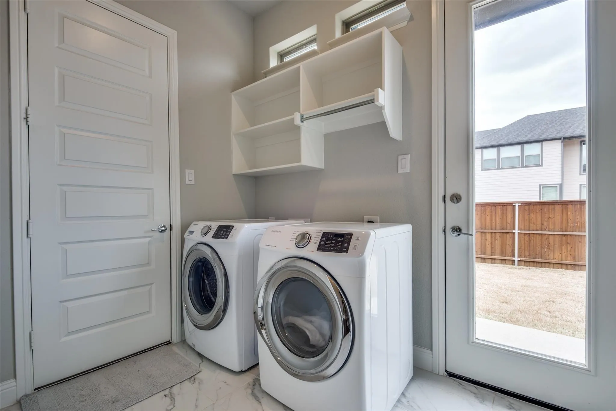 Modern laundry room featuring side-by-side front-load washer and dryer with stainless steel accents and digital controls
