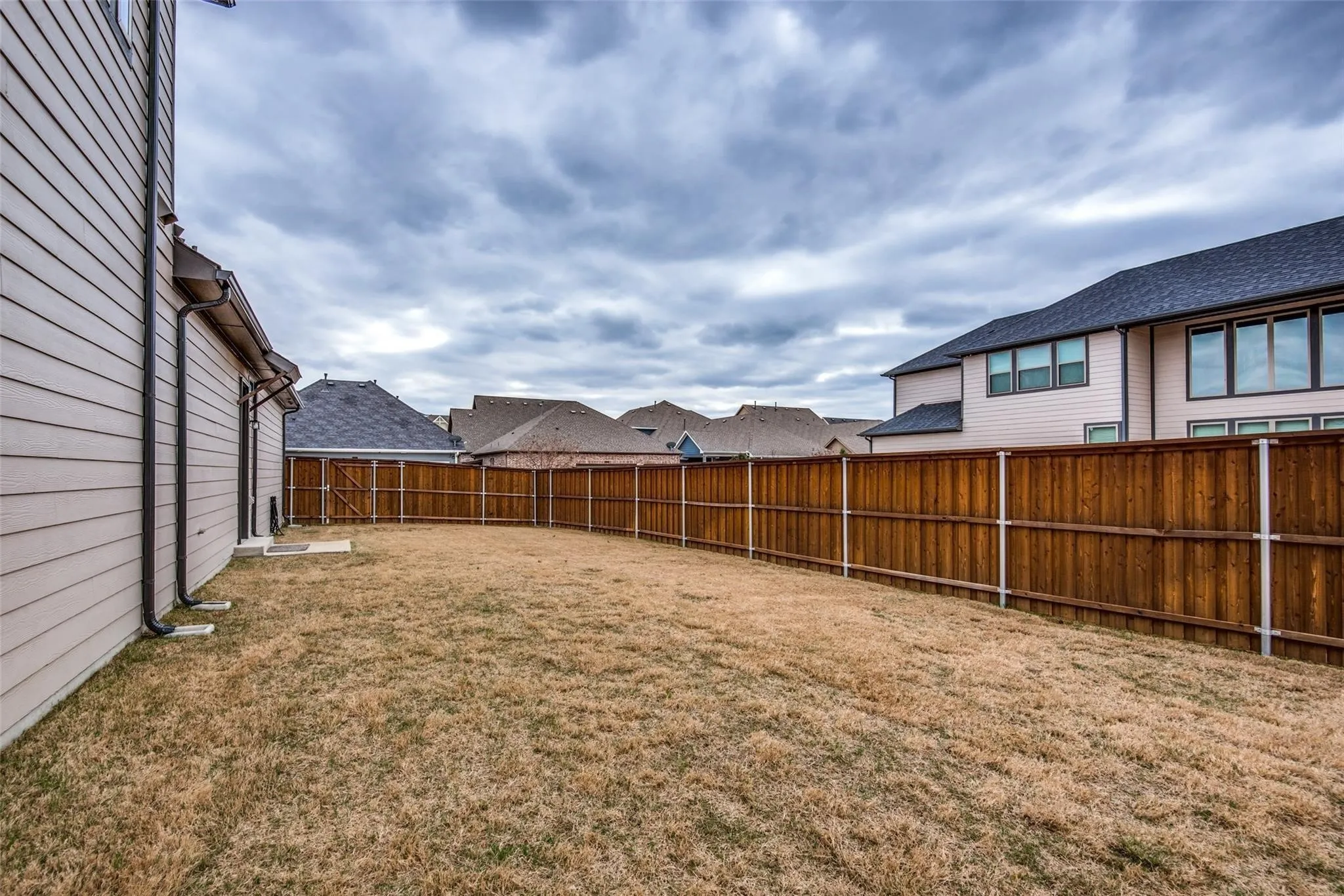 Spacious backyard featuring a level lawn and sturdy wood-finish privacy fencing with metal posts