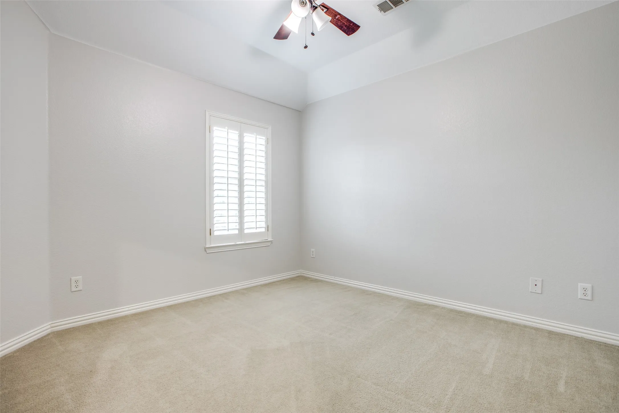 Spacious bedroom featuring neutral wall finishes, neutral carpet flooring, and abundant natural light from a shuttered window