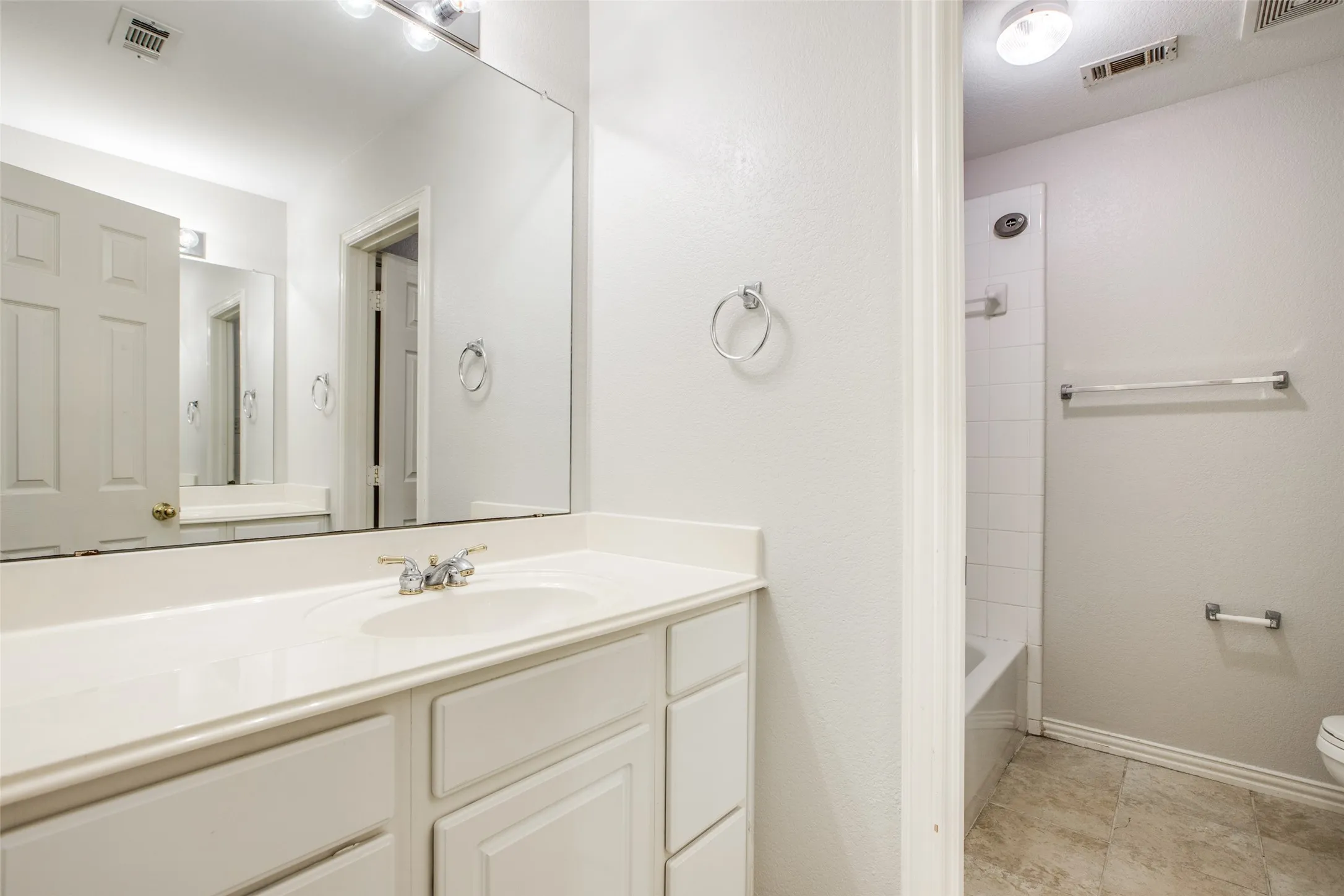 Spa-inspired master bathroom featuring an expansive vanity with dual sinks, abundant storage cabinetry, and a large framed mirror with integrated lighting
