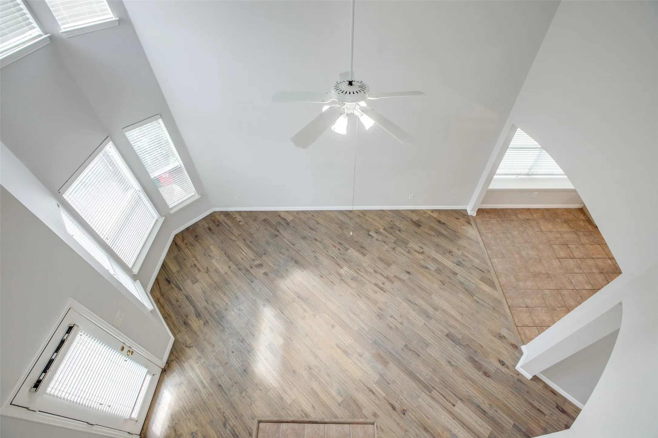 Soaring ceilings with a white ceiling fan and multiple windows for abundant illumination