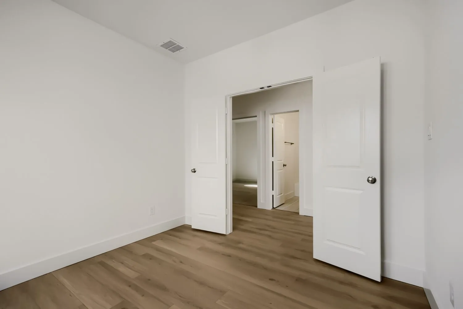 Light wood-finish flooring, white painted walls, and white trim throughout