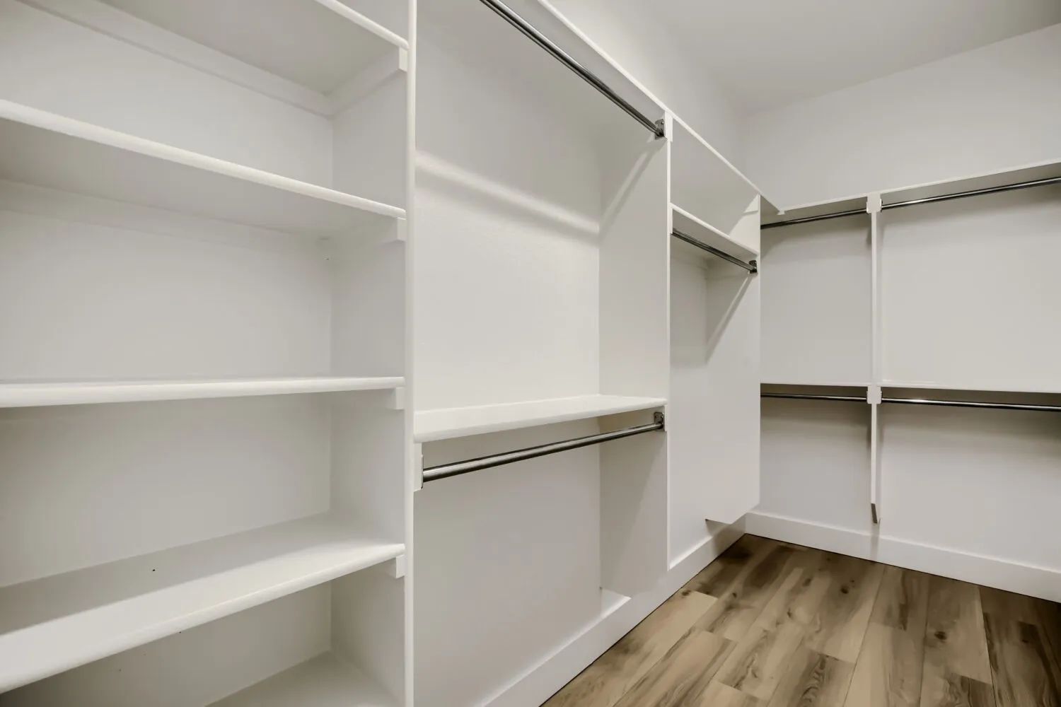 Built-in shelving, chrome hanging rods, wood-finish flooring, and crisp white walls