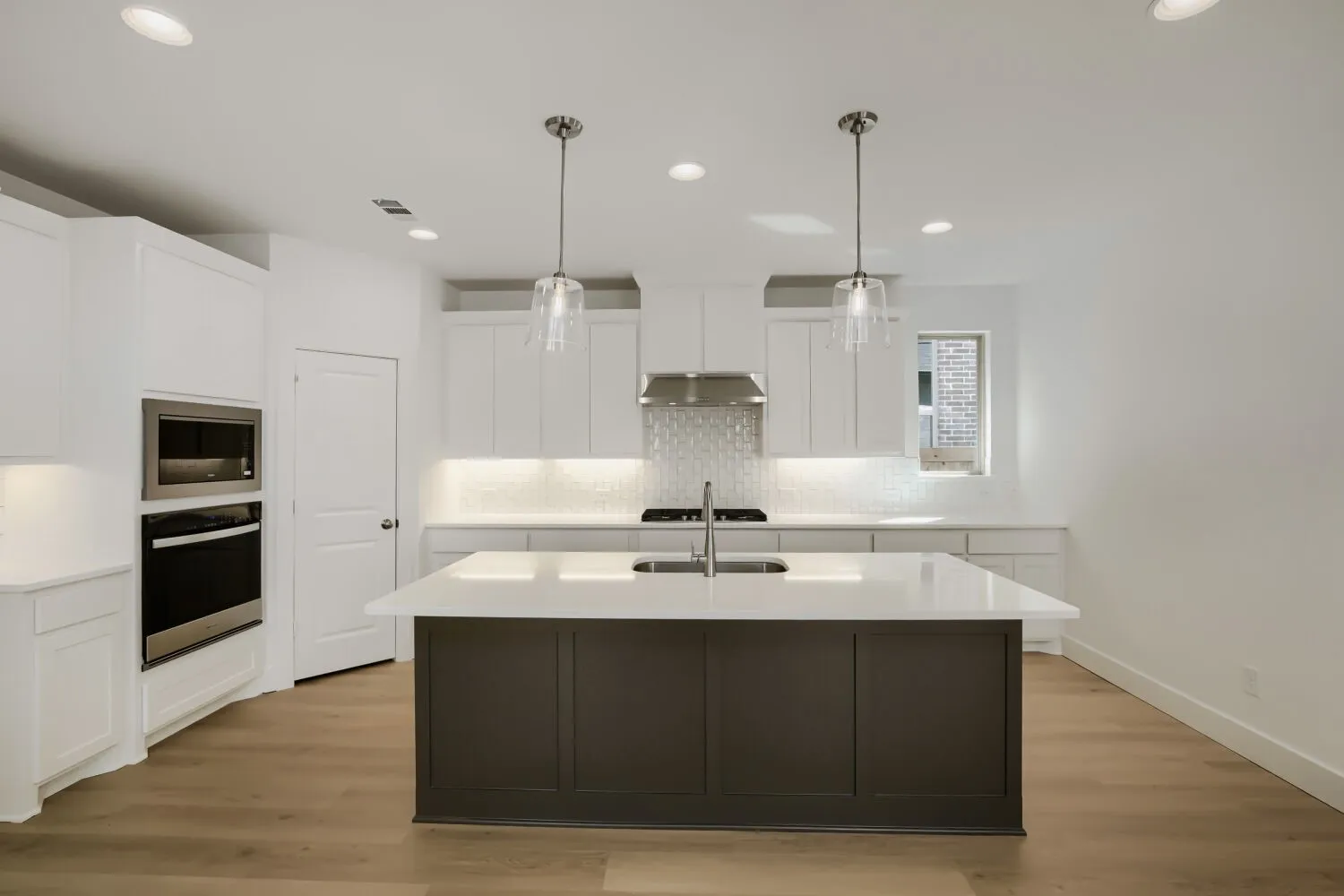 Kitchen featuring a central island, white shaker-style cabinetry, stainless steel appliances, and wood-finish flooring