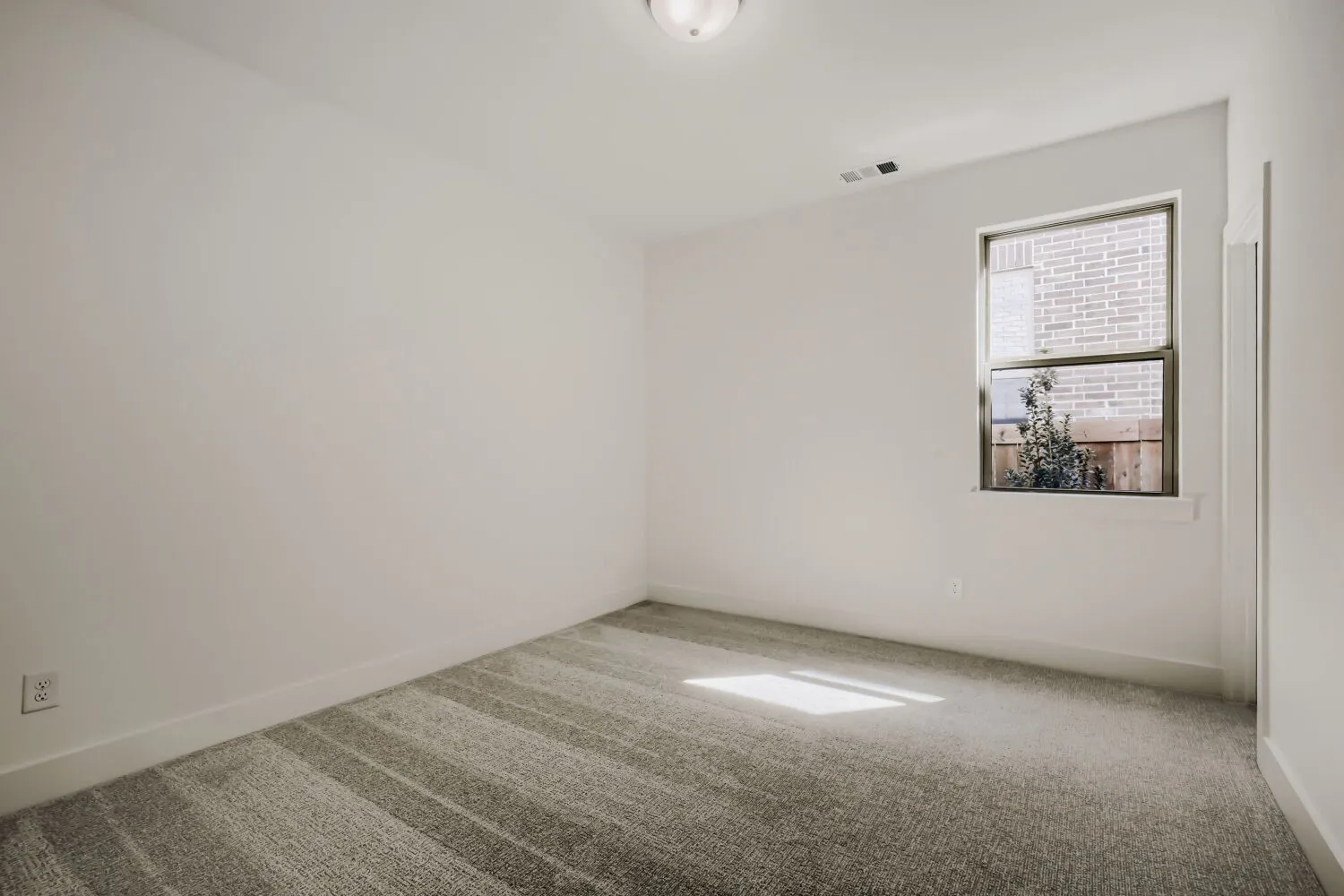 Neutral wall paint, patterned carpet flooring, single window, flush mount ceiling light fixture, and white baseboards