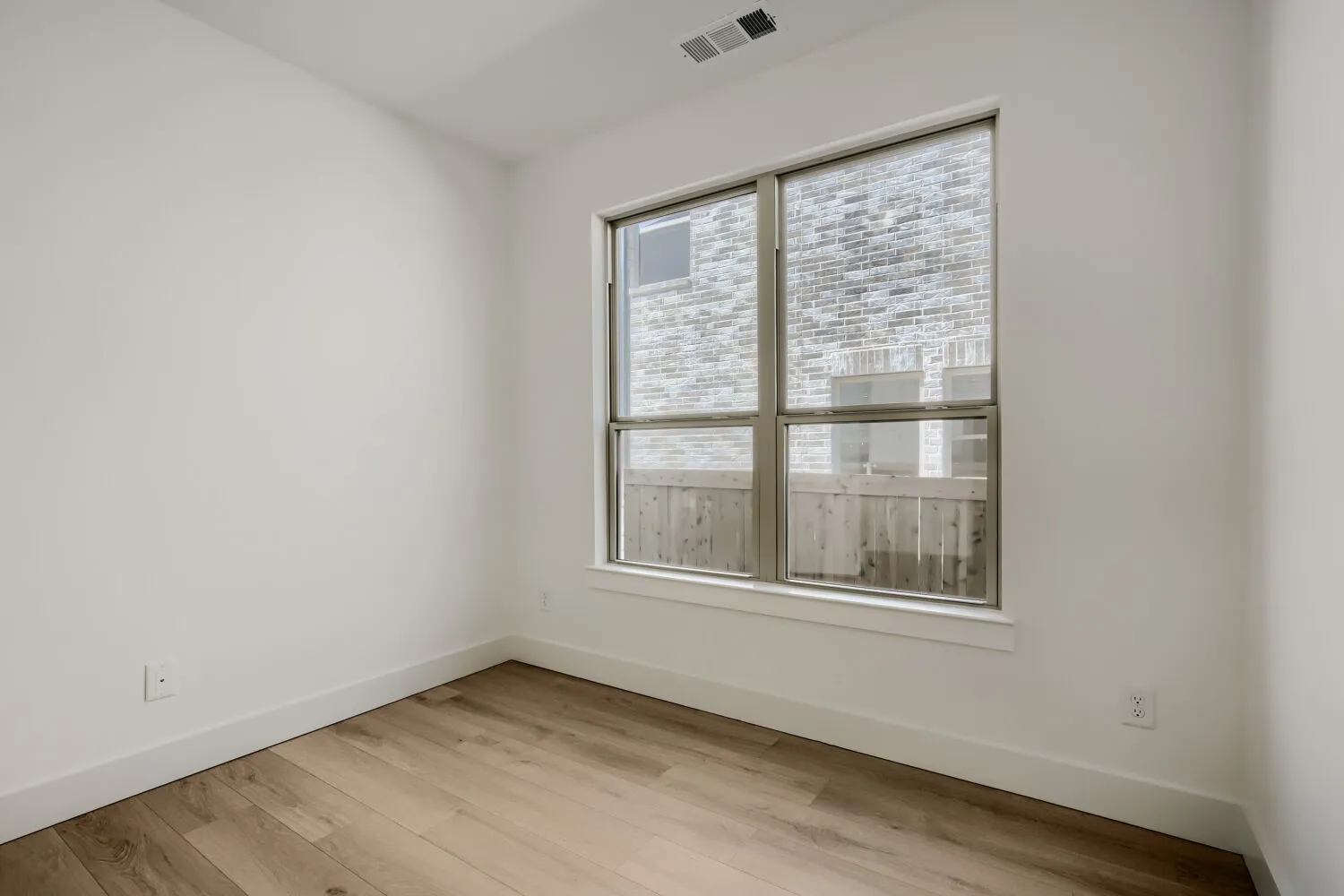 Hardwood-finish flooring, white walls, and a large window