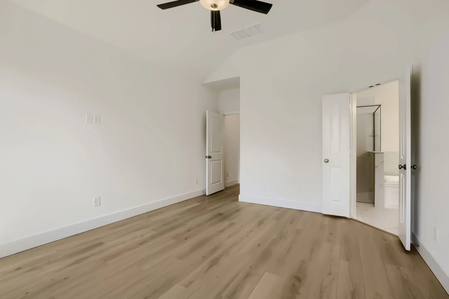Vaulted ceiling with a flush-mount ceiling fan, wood-finish flooring, and white paneled doors