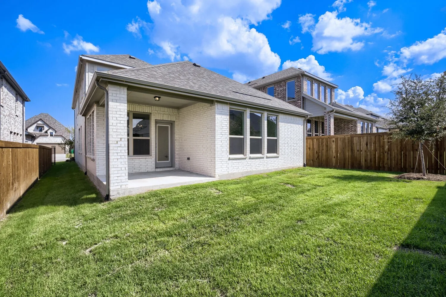Spacious backyard featuring a covered patio, extensive lawn, and wood privacy fencing