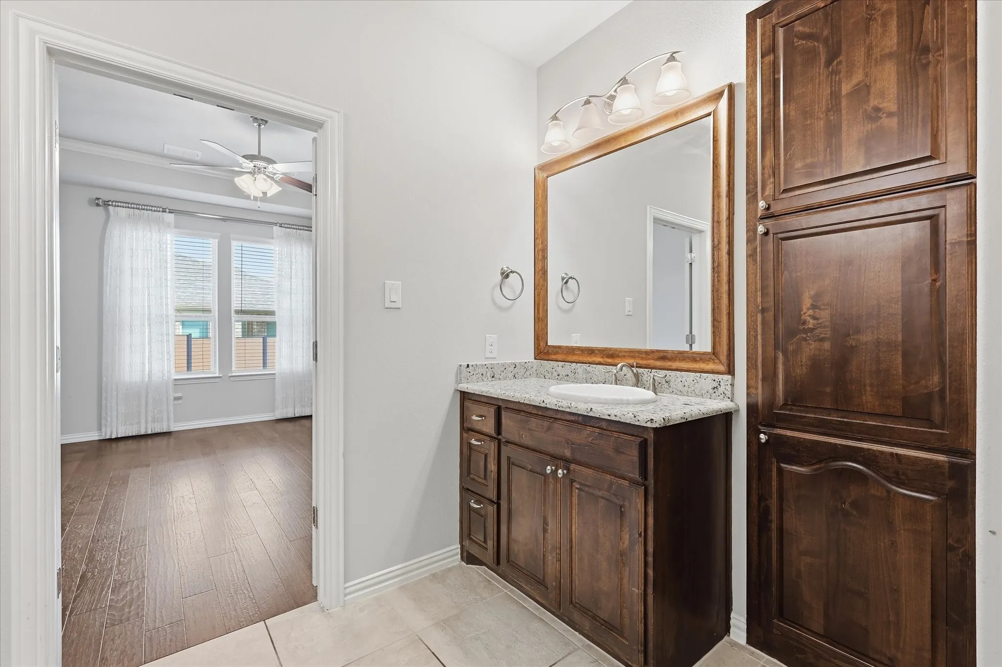 Bathroom vanity with a granite-style countertop, undermount sink, and a framed mirror