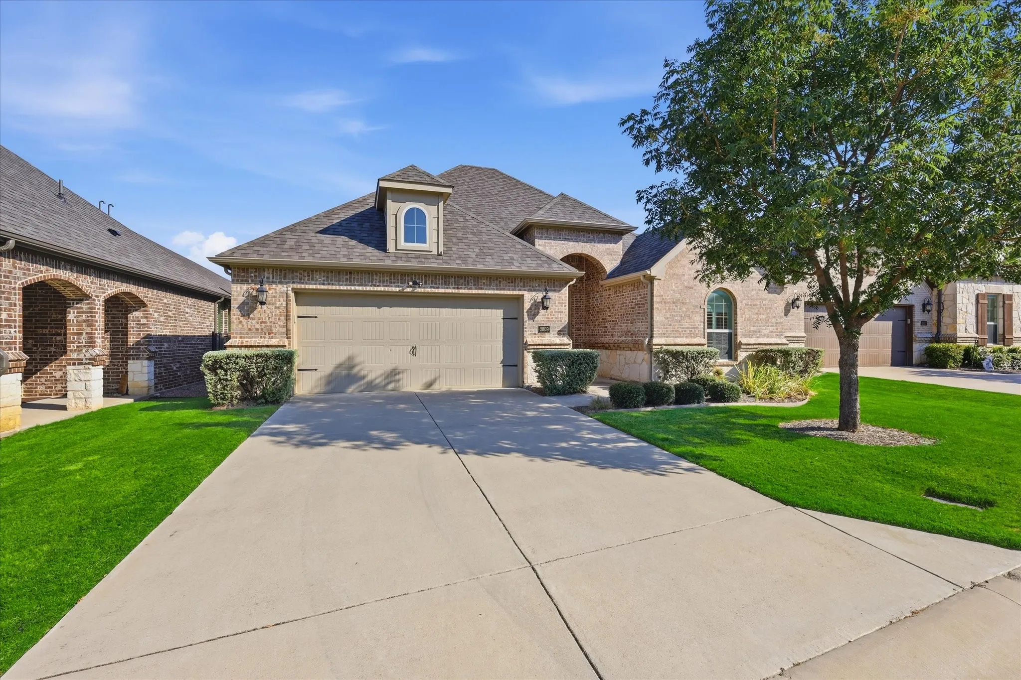 Brick exterior with a dormer window, an arched window, and an attached garage
