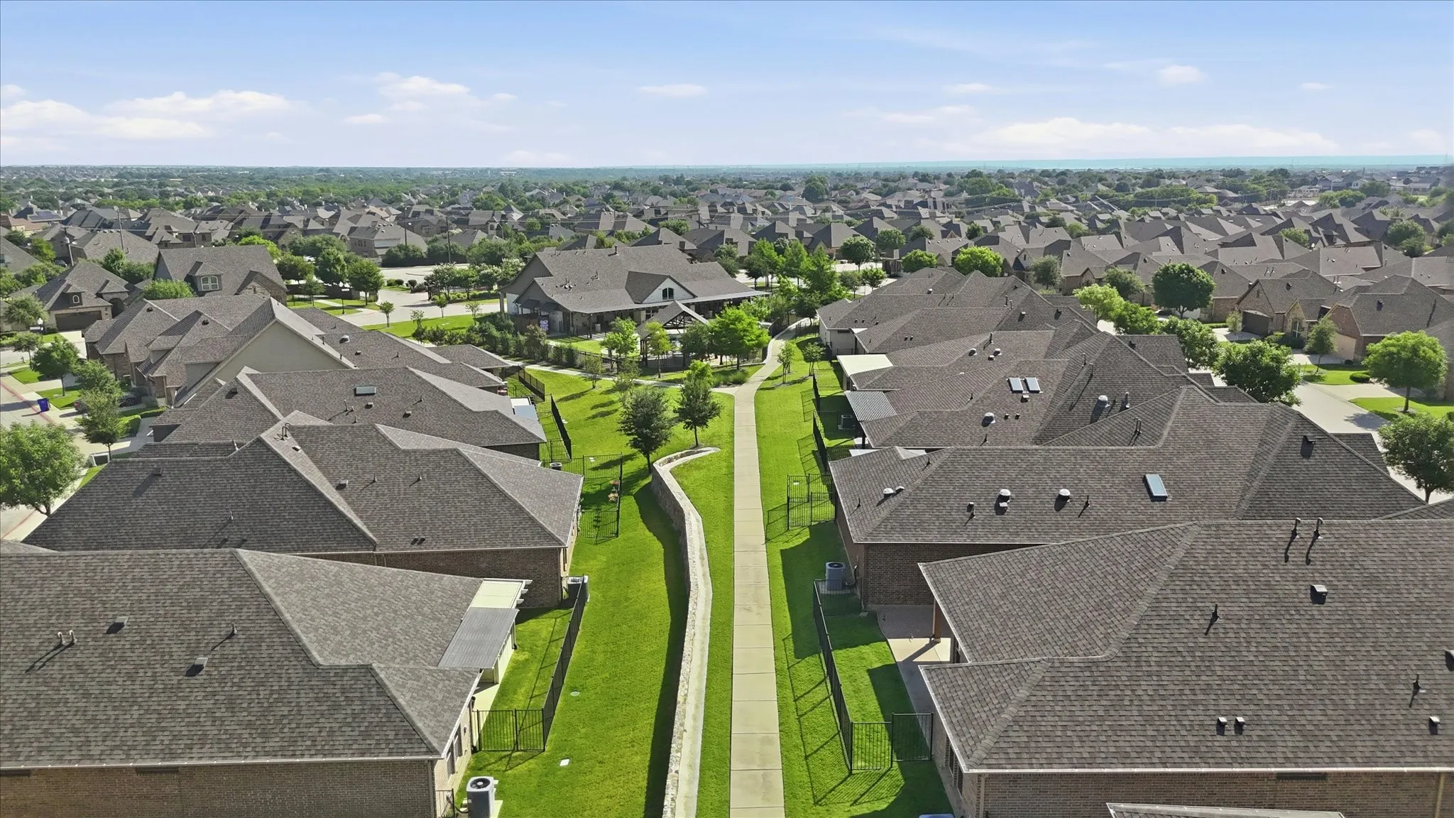 Expansive residential area featuring numerous homes with dark shingle roofs, brick exteriors, and well-maintained green spaces