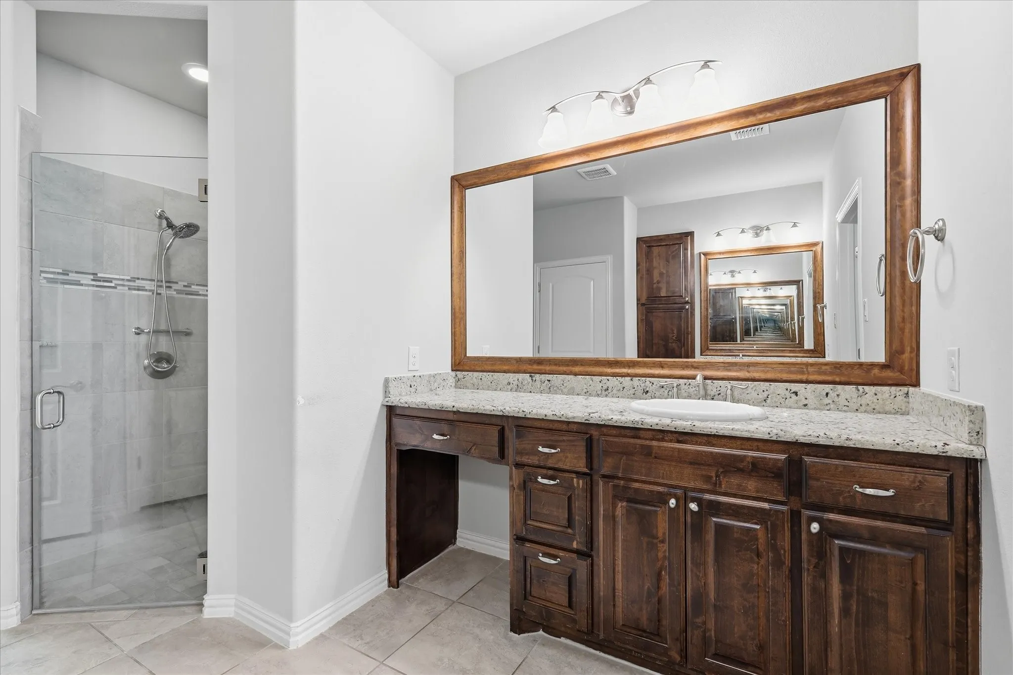 Bathroom featuring a dark wood-finish vanity with a light speckled countertop and undermount sink