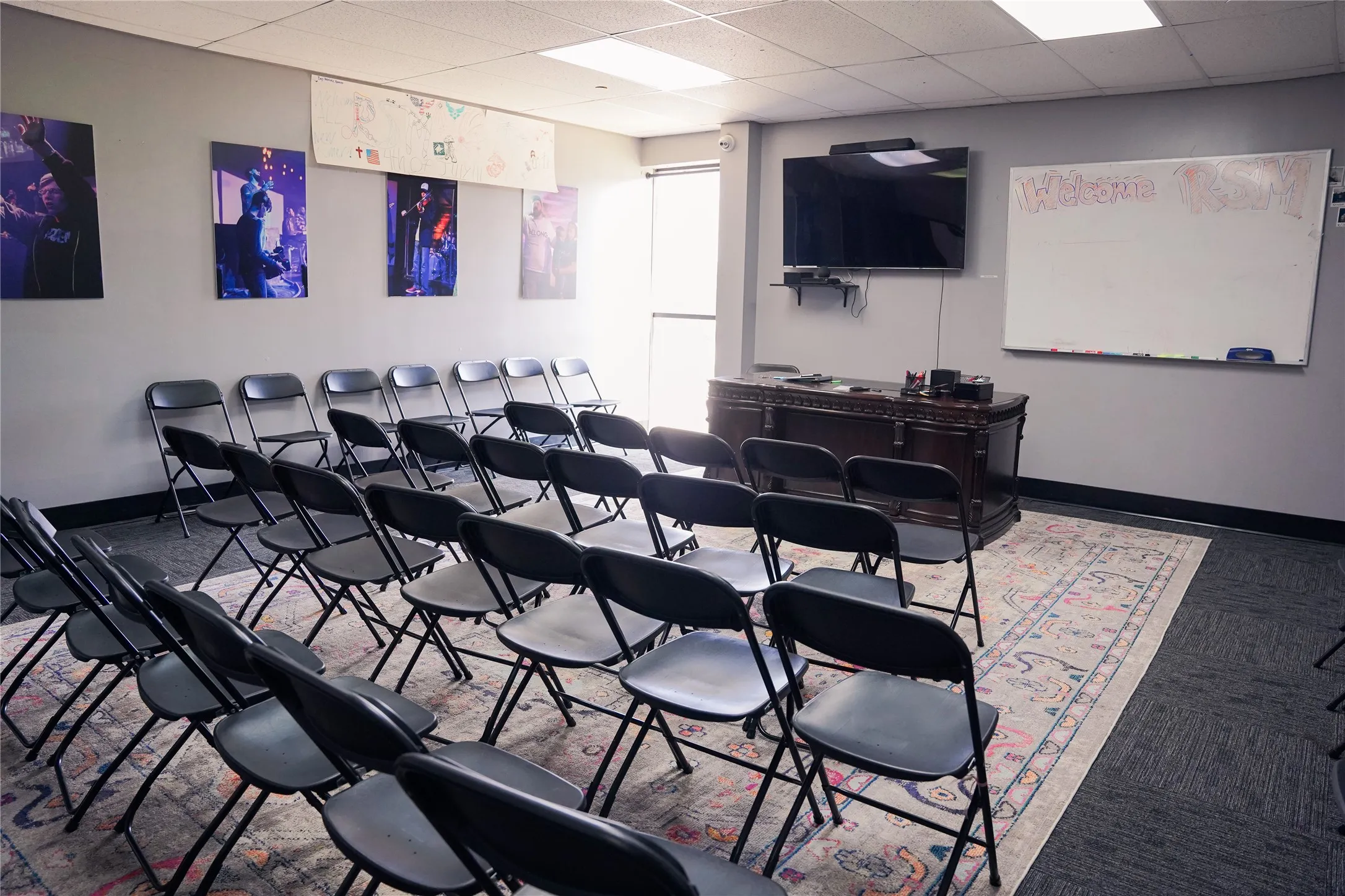 Spacious room featuring neutral gray walls and a combination of patterned area rug and dark gray carpet