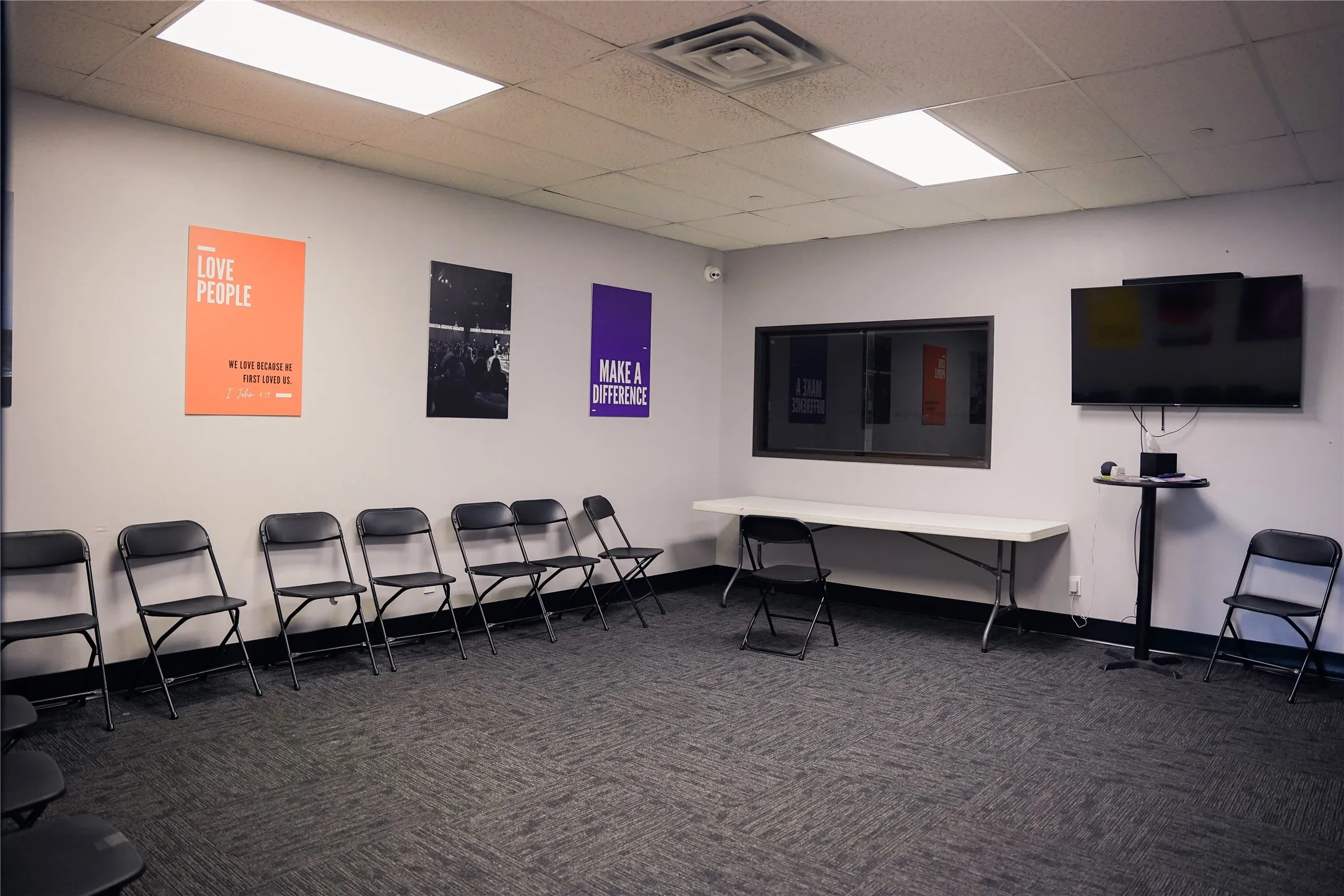 Spacious room featuring textured carpet flooring, white walls, and a dropped ceiling with recessed lighting