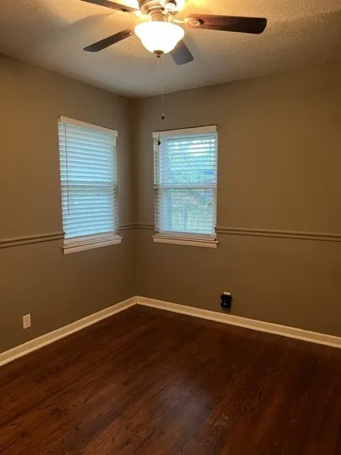 Interior room featuring wood-finish flooring and two windows with blinds
