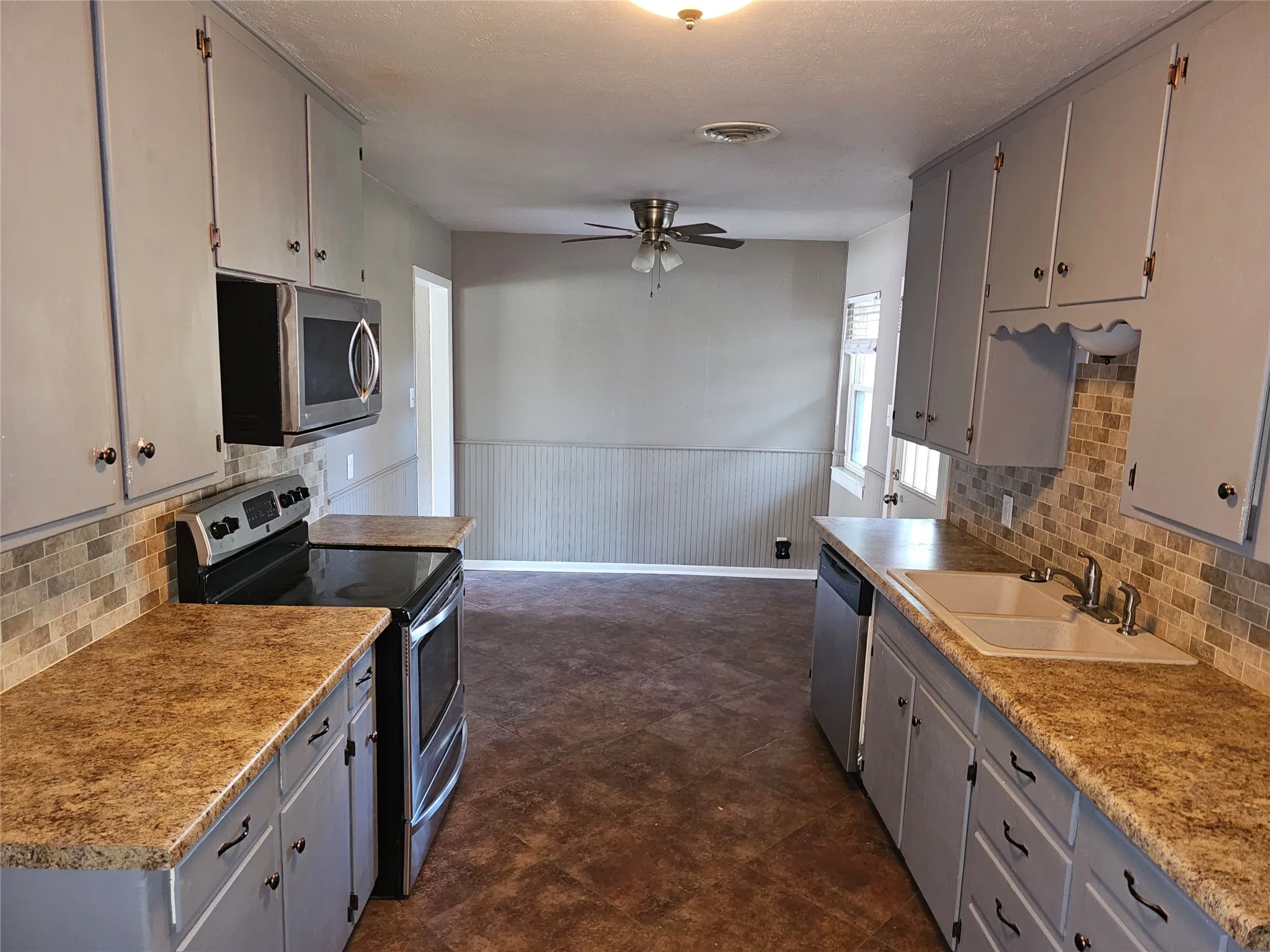 Galley-style kitchen featuring dual stainless steel ranges, abundant cabinetry with soft-close doors, granite countertops, and tile backsplash