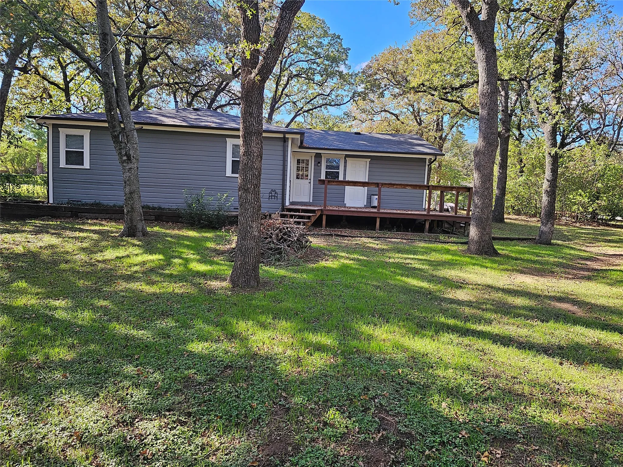 Charming mobile home situated on a spacious, tree-lined lot featuring mature oak trees providing natural shade throughout the grounds