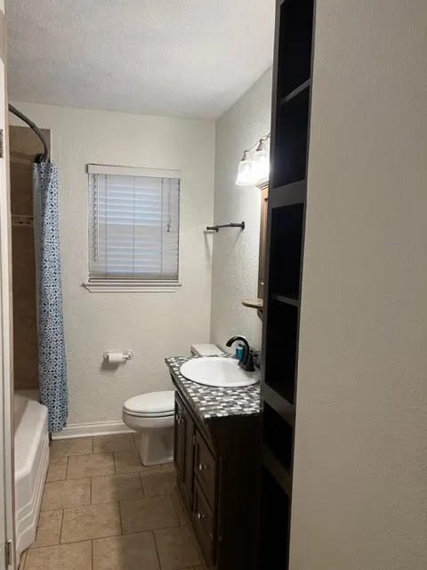 Bathroom featuring a dark wood vanity with a mosaic tile countertop, an undermount sink, and a black faucet