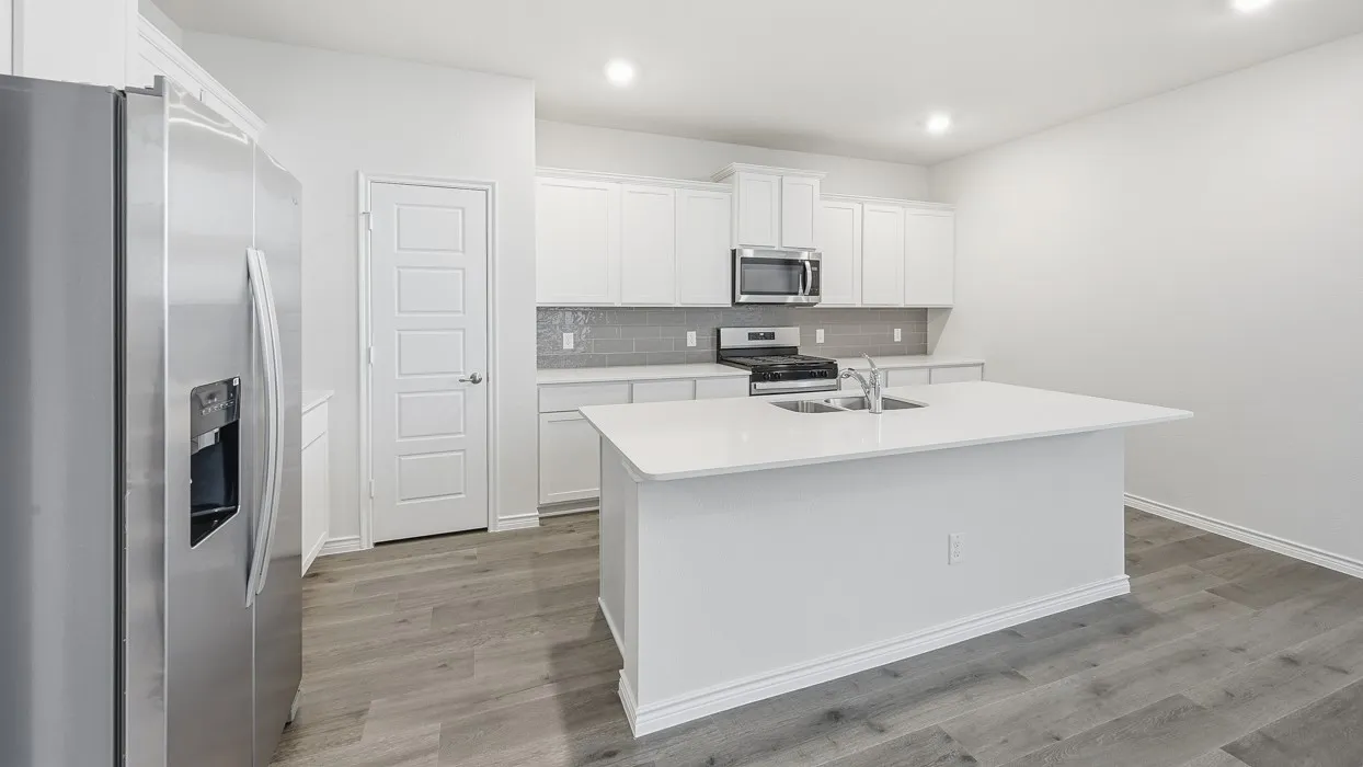 Modern kitchen featuring stainless steel appliances, white cabinetry, a large center island with an undermount sink, a gray tile backsplash, and wood-finish flooring