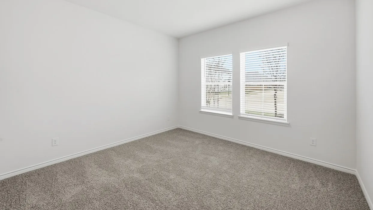Bright bedroom with plush carpeting in neutral tones and dual windows featuring plantation shutters, allowing abundant natural light throughout the space