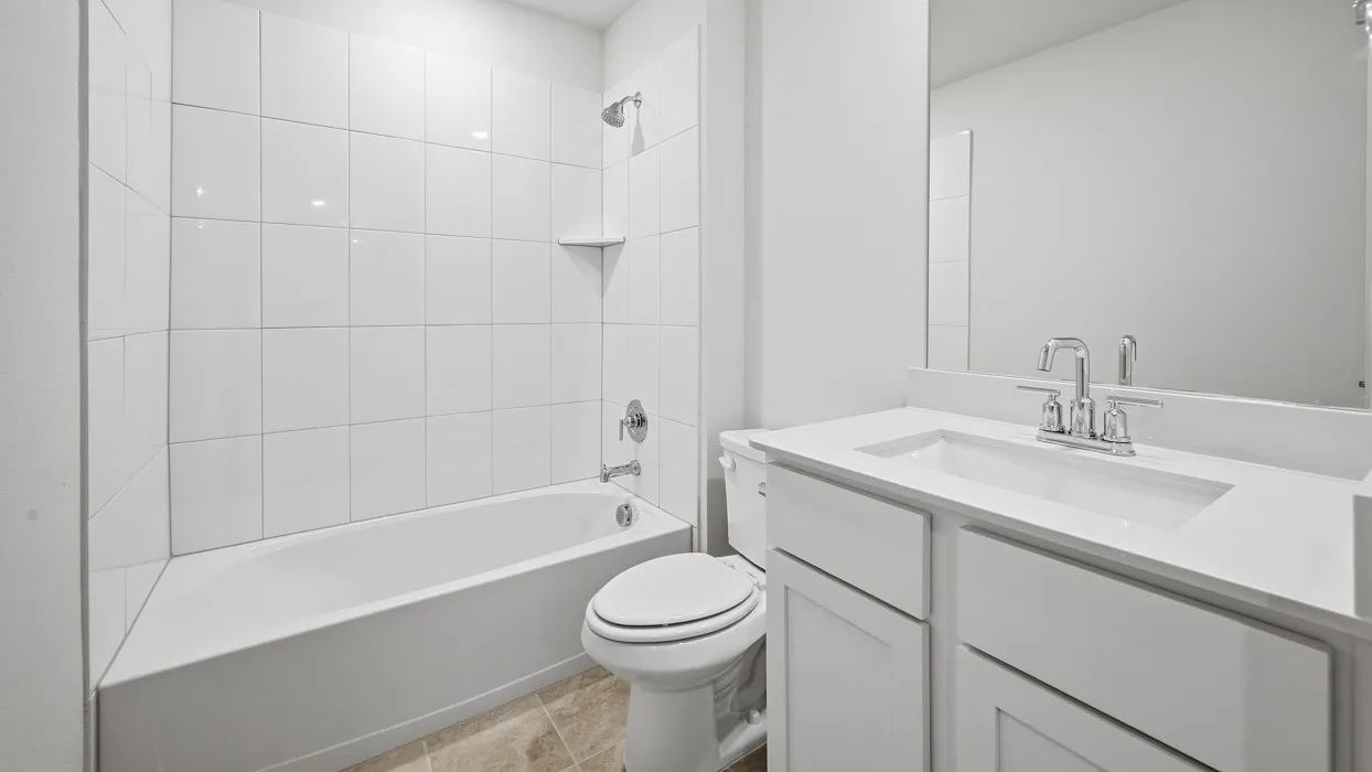 Clean and functional bathroom featuring white subway tile walls, a ceramic toilet with elongated bowl, and a vanity with rectangular undermount sink paired with a chrome two-handle faucet
