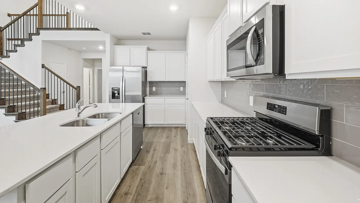 Contemporary kitchen featuring a large island with an undermount double sink, white cabinetry, integrated stainless steel appliances, and wood-finish flooring