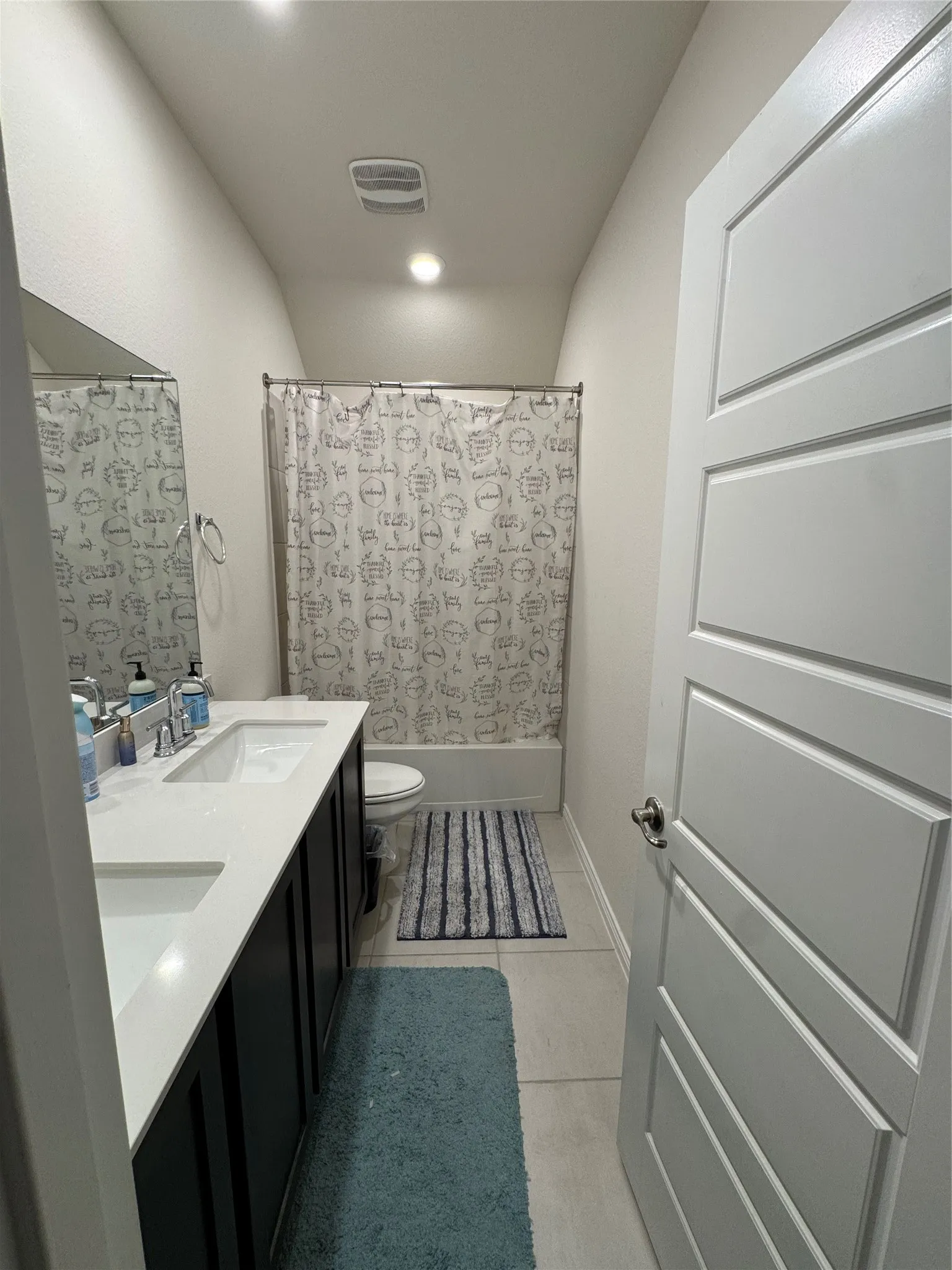 Bathroom featuring double vanity, tile patterned floors, and shower / bathtub combination with curtain