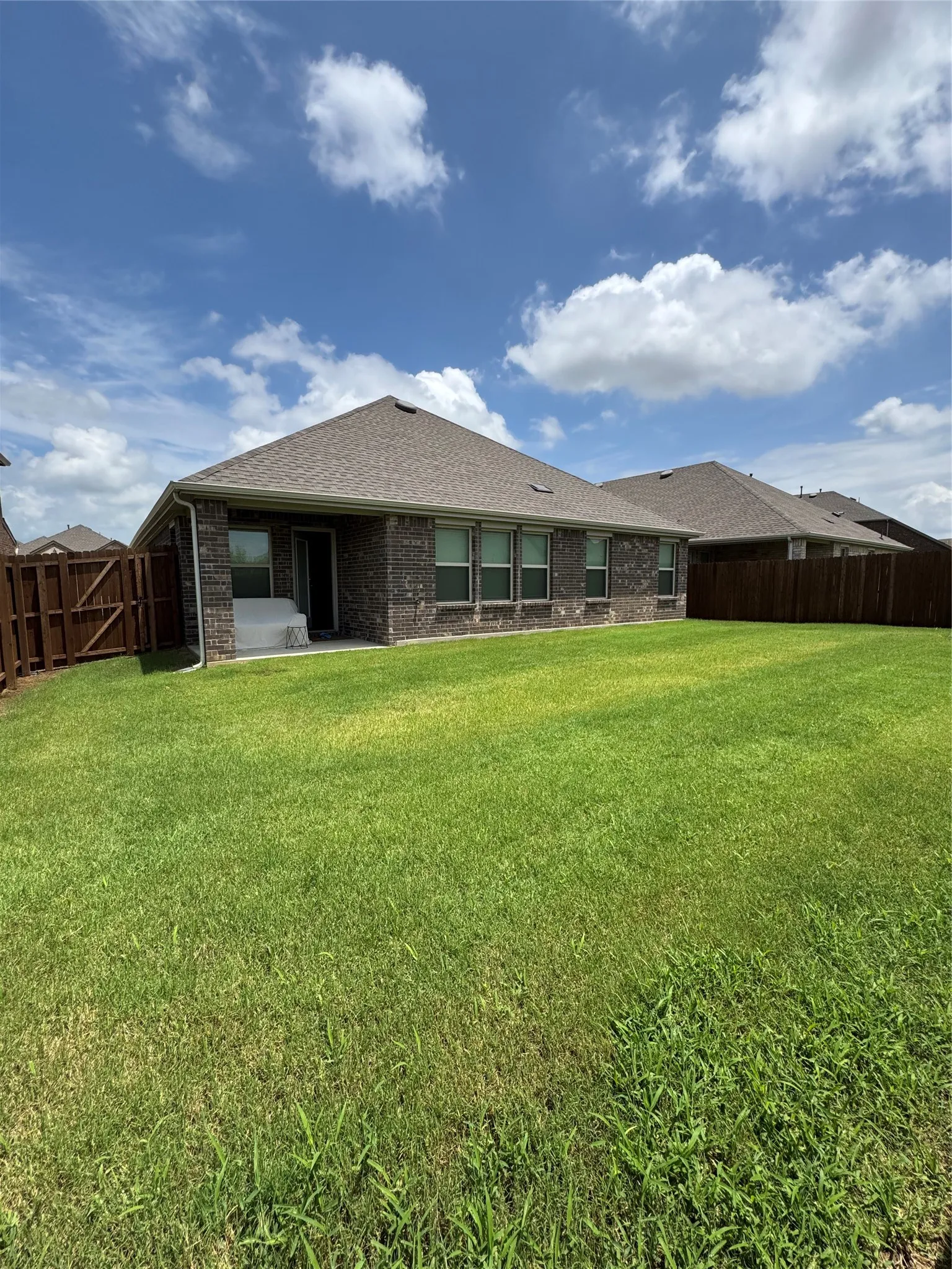 Rear view of property featuring brick siding and roof with shingles