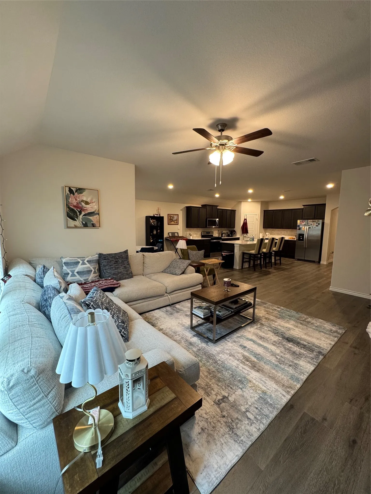 Living area with dark wood-type flooring, ceiling fan, recessed lighting, and lofted ceiling