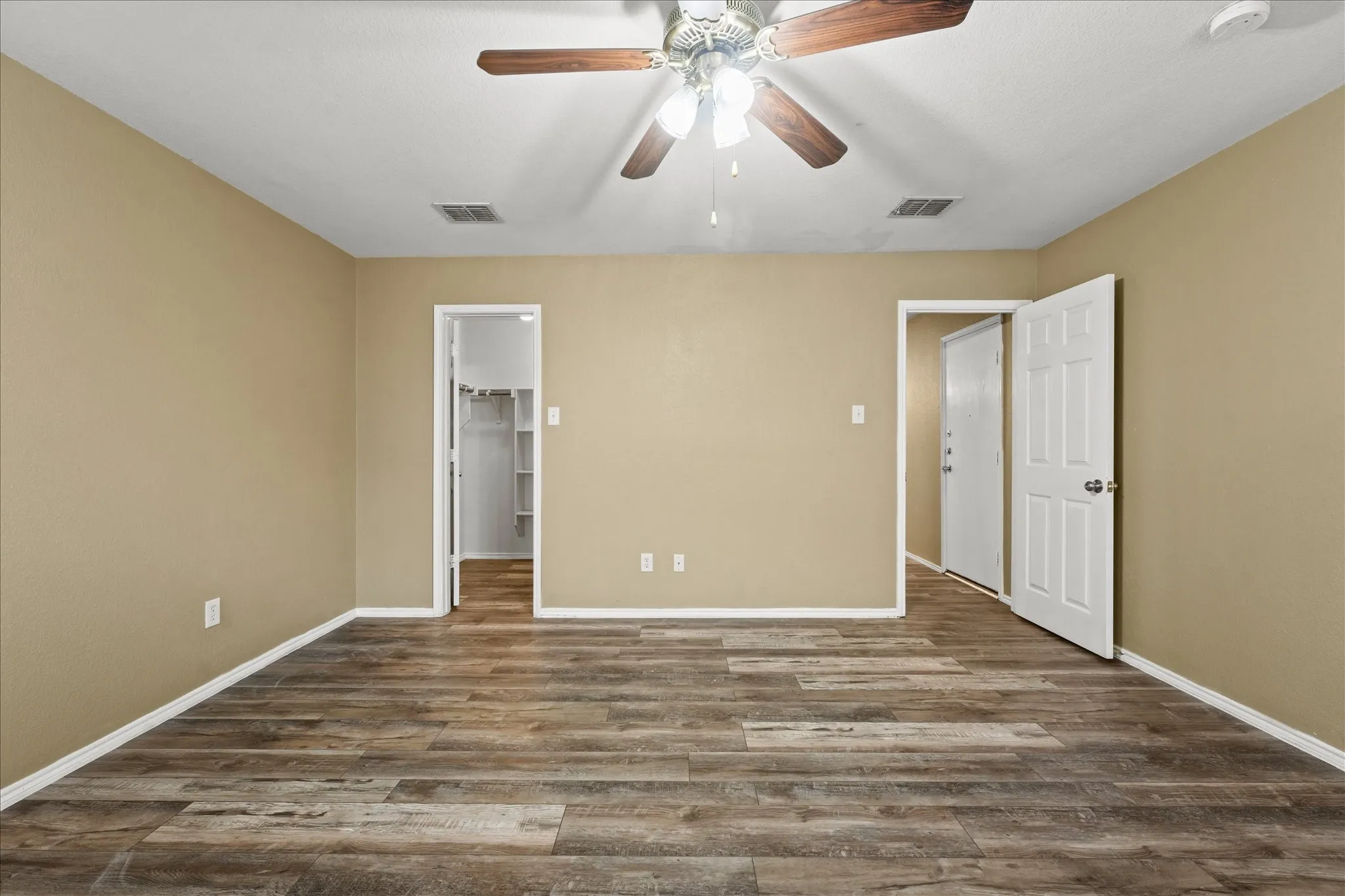 Unfurnished bedroom with wood finished floors, a ceiling fan, a spacious closet, and a closet