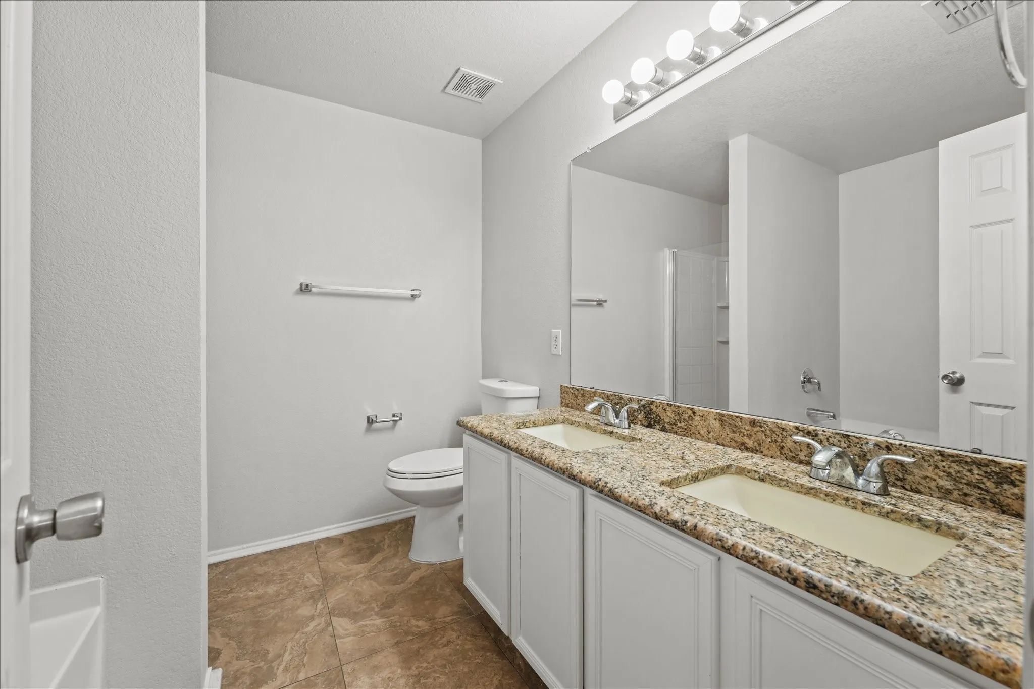 Full bath with double vanity and a shower
