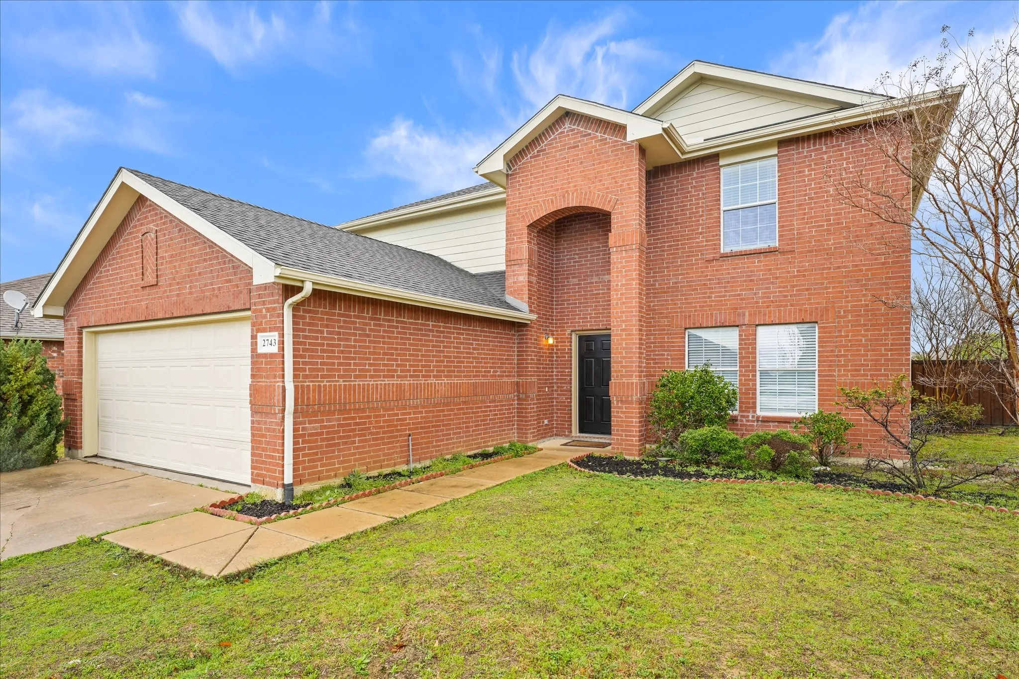 Traditional home with a garage, a front lawn, brick siding, driveway, and roof with shingles