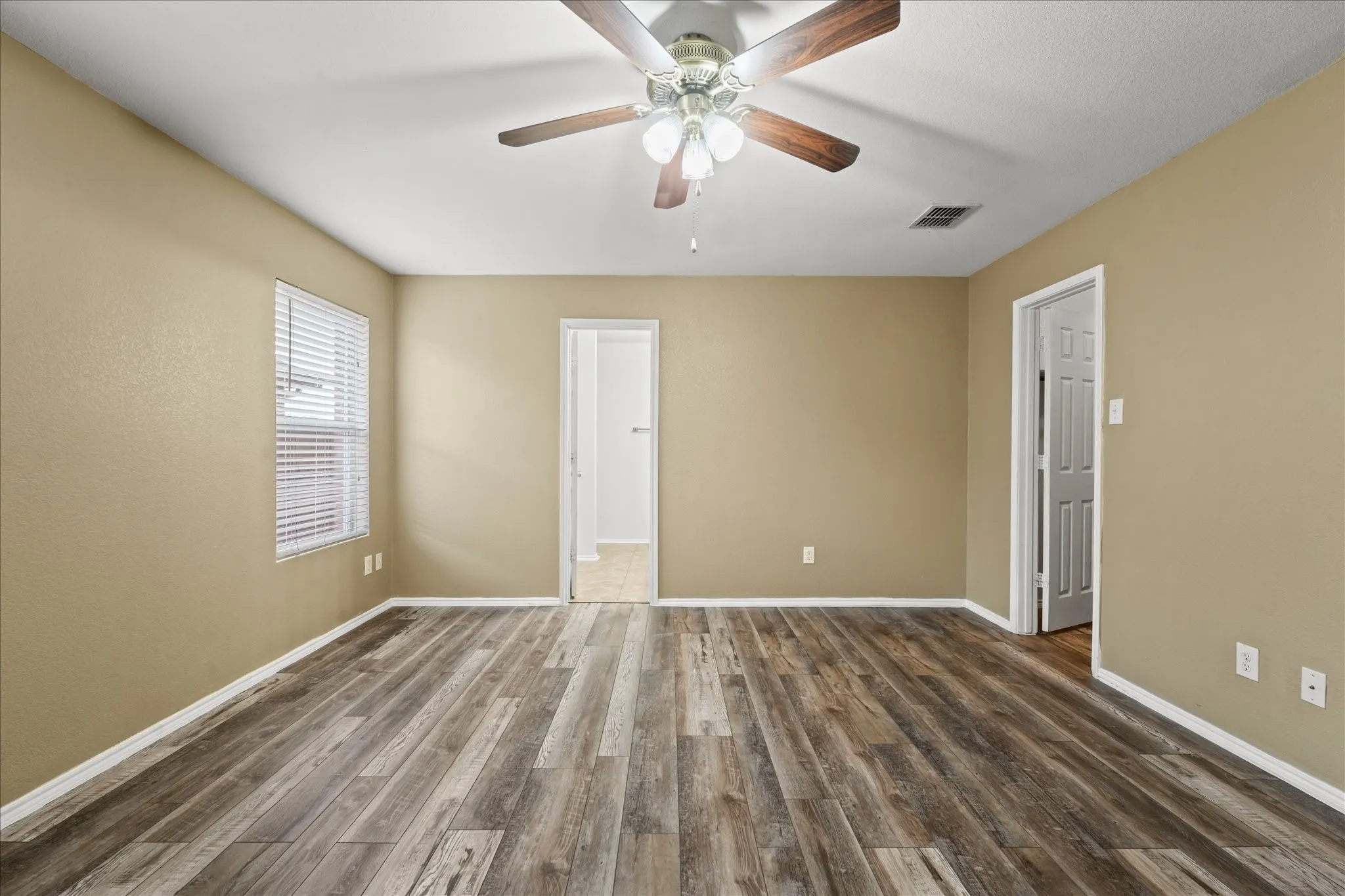 Empty room with dark wood finished floors and a ceiling fan