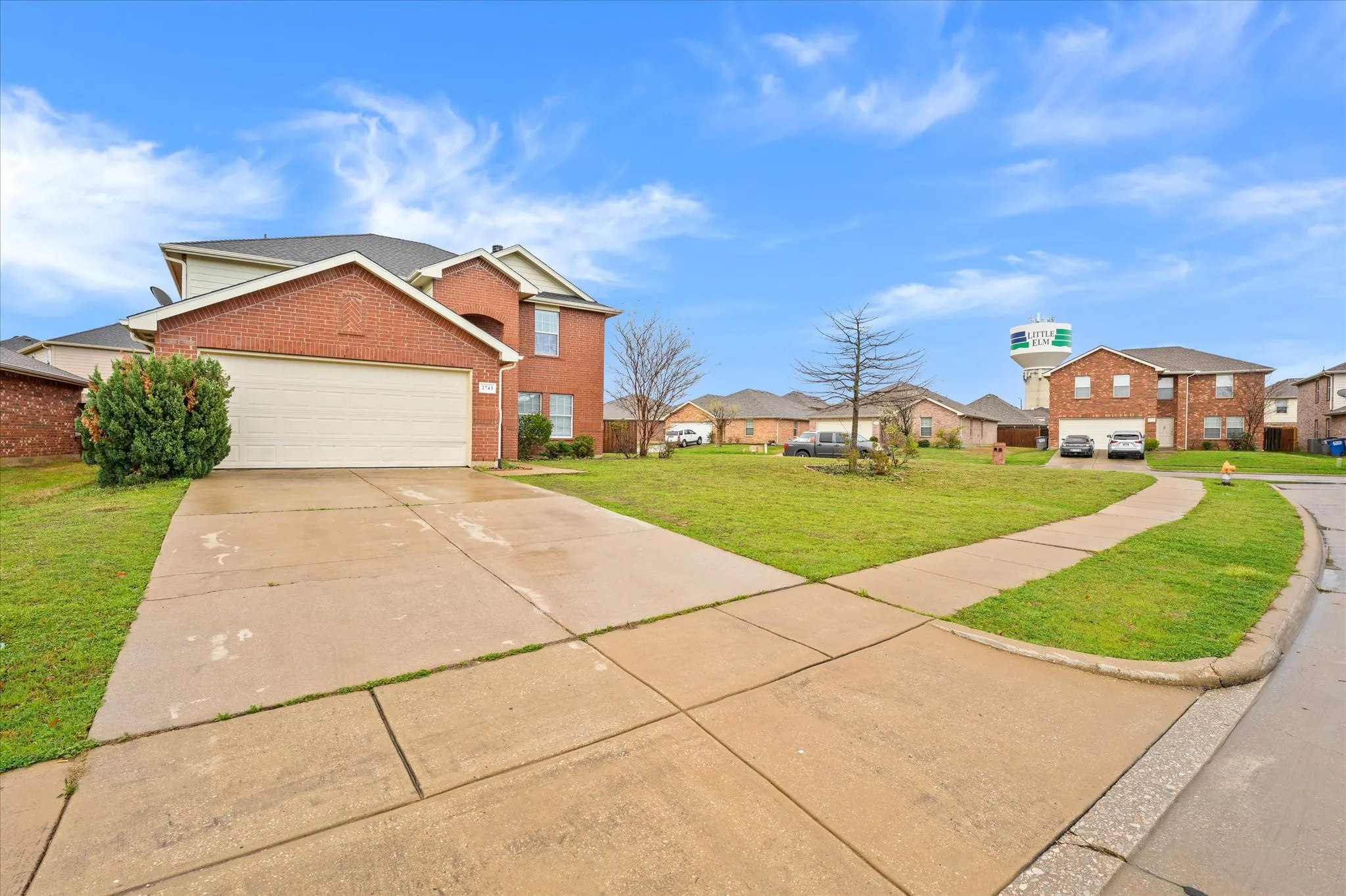 View of front of property with brick siding, a front lawn, driveway, a residential view, and an attached garage