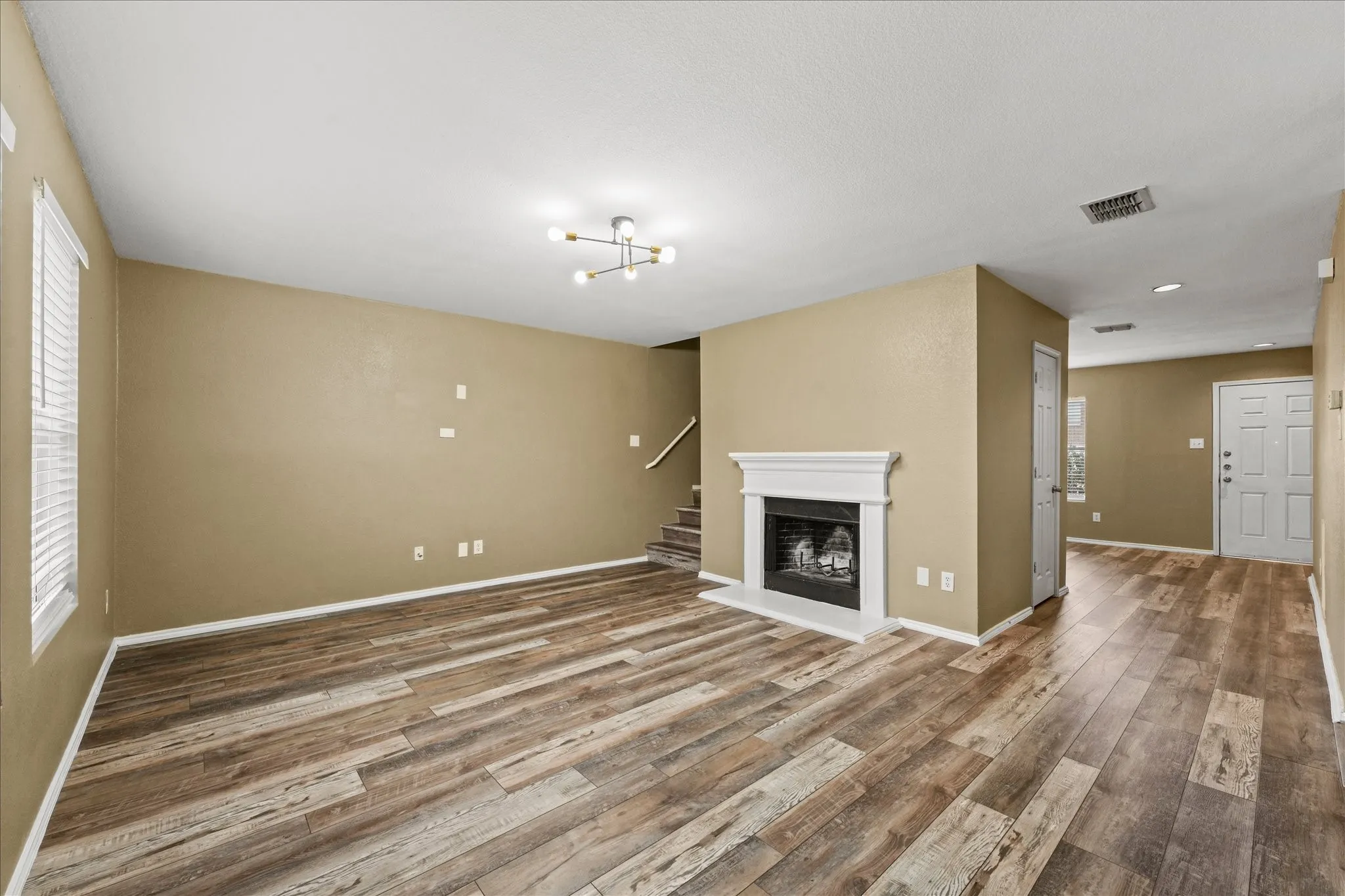 Unfurnished living room featuring wood finished floors, a chandelier, plenty of natural light, and recessed lighting