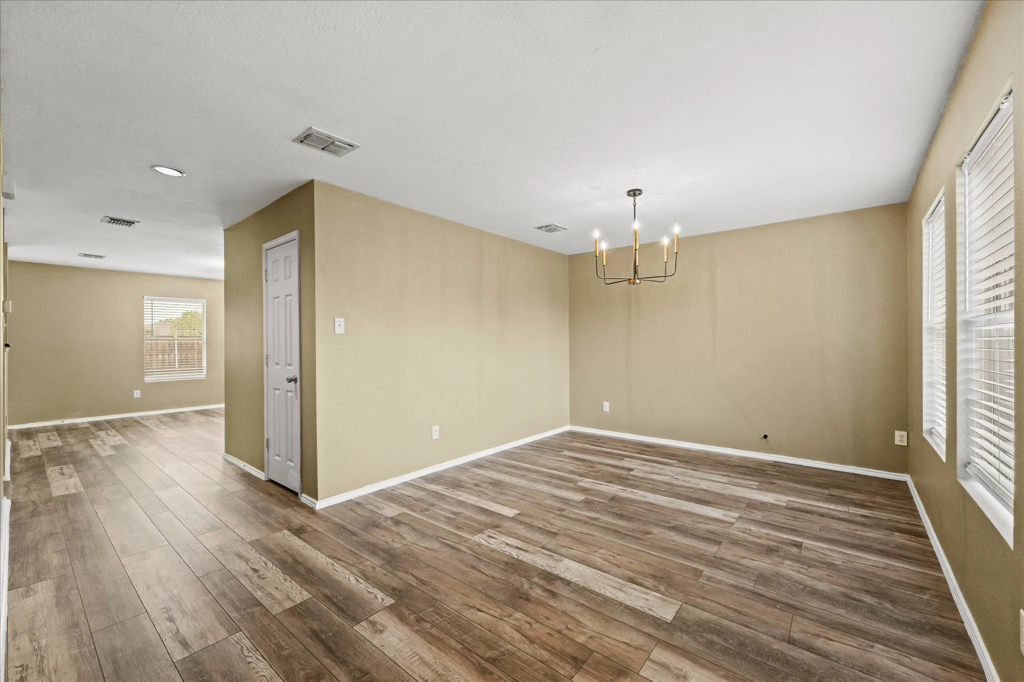 Empty room with a chandelier, dark wood-style floors, and recessed lighting