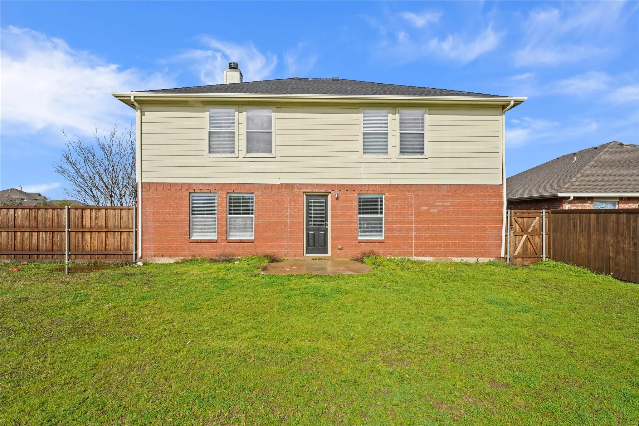 Rear view of house with a fenced backyard, a chimney, and brick siding