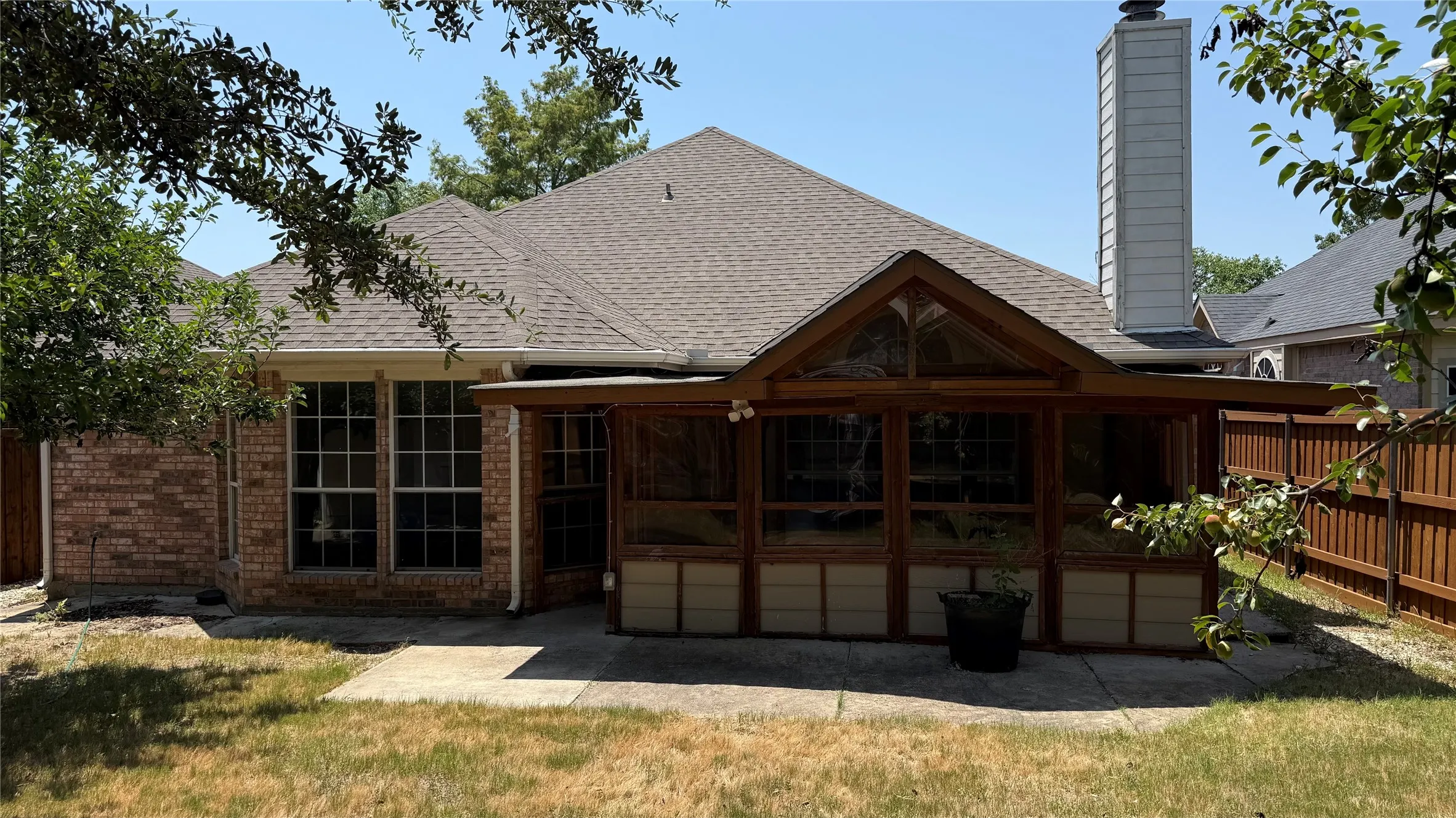 Elegant brick exterior with a gabled roofline and substantial covered porch featuring multiple French doors and windows