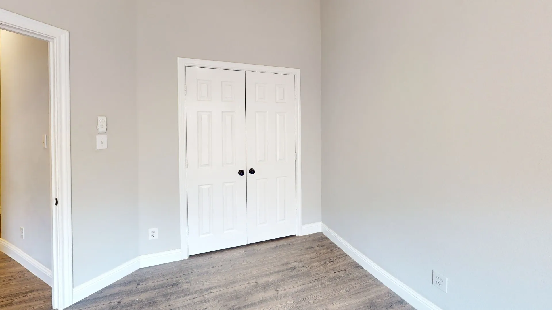 Interior space featuring light gray walls, wood-finish flooring, and white baseboards