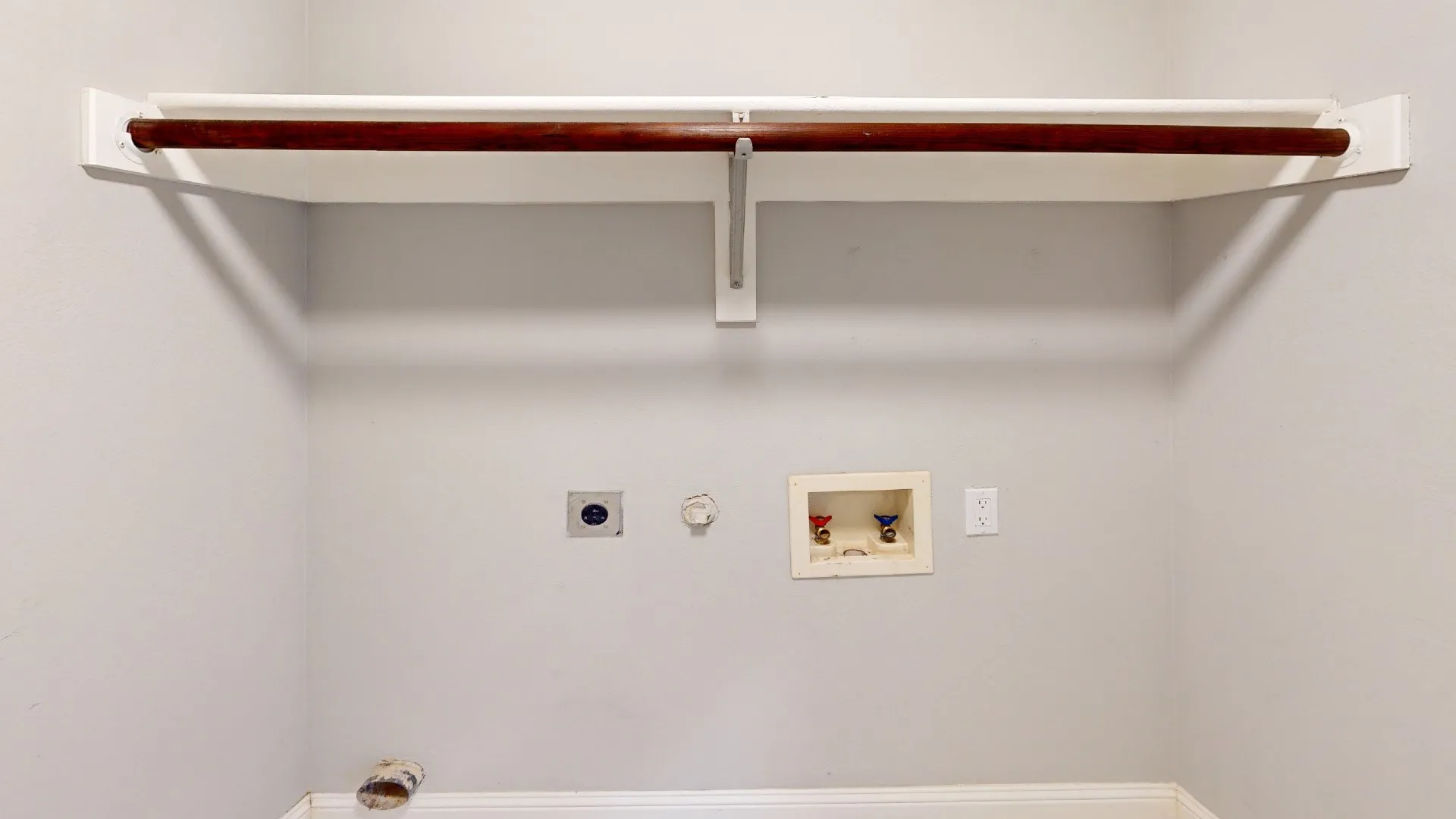 Dedicated laundry area featuring a wood-finish hanging rod, upper shelf, and utility connections